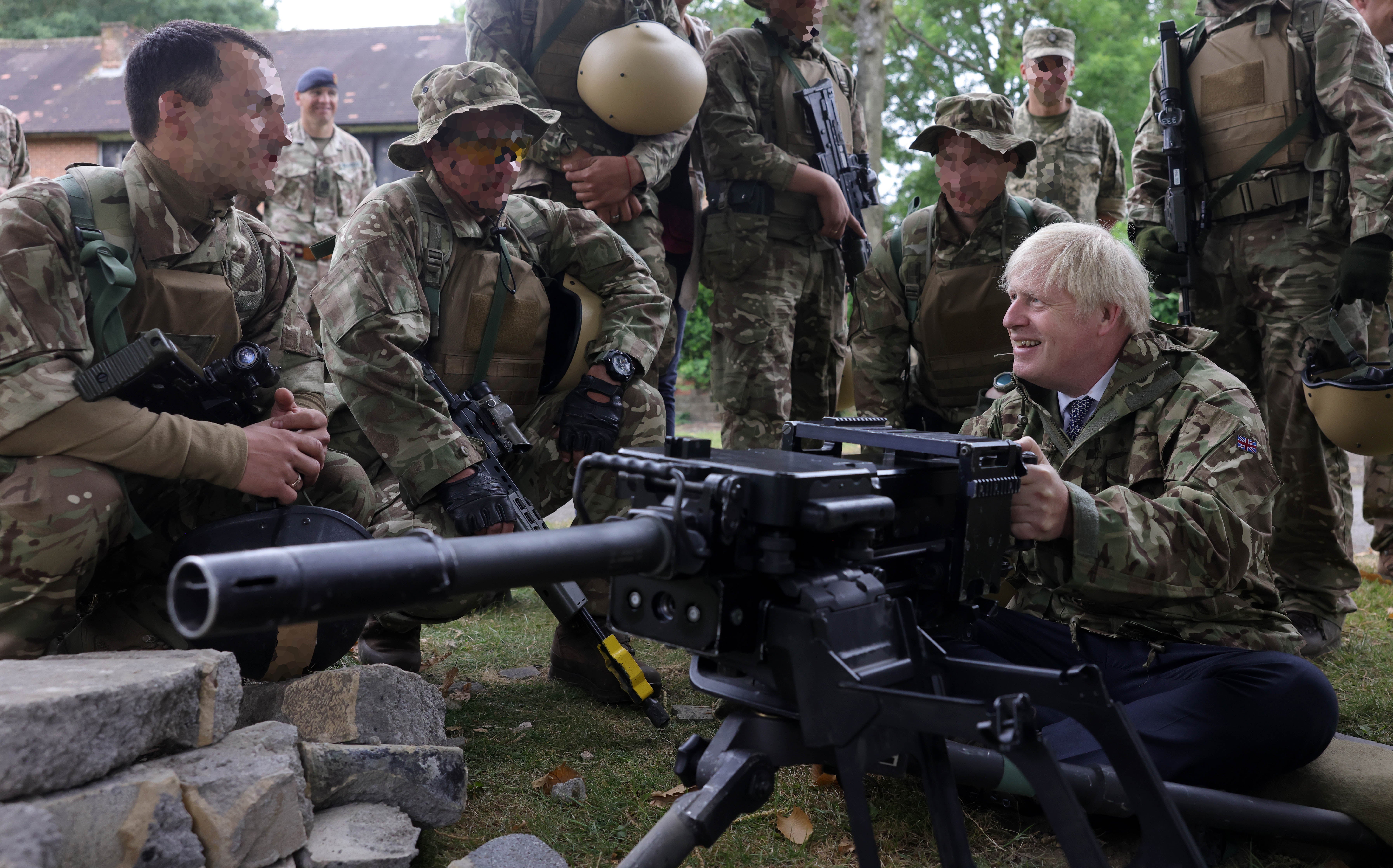 Mr Johnson poses with military equipment surrounded by members of the armed forces