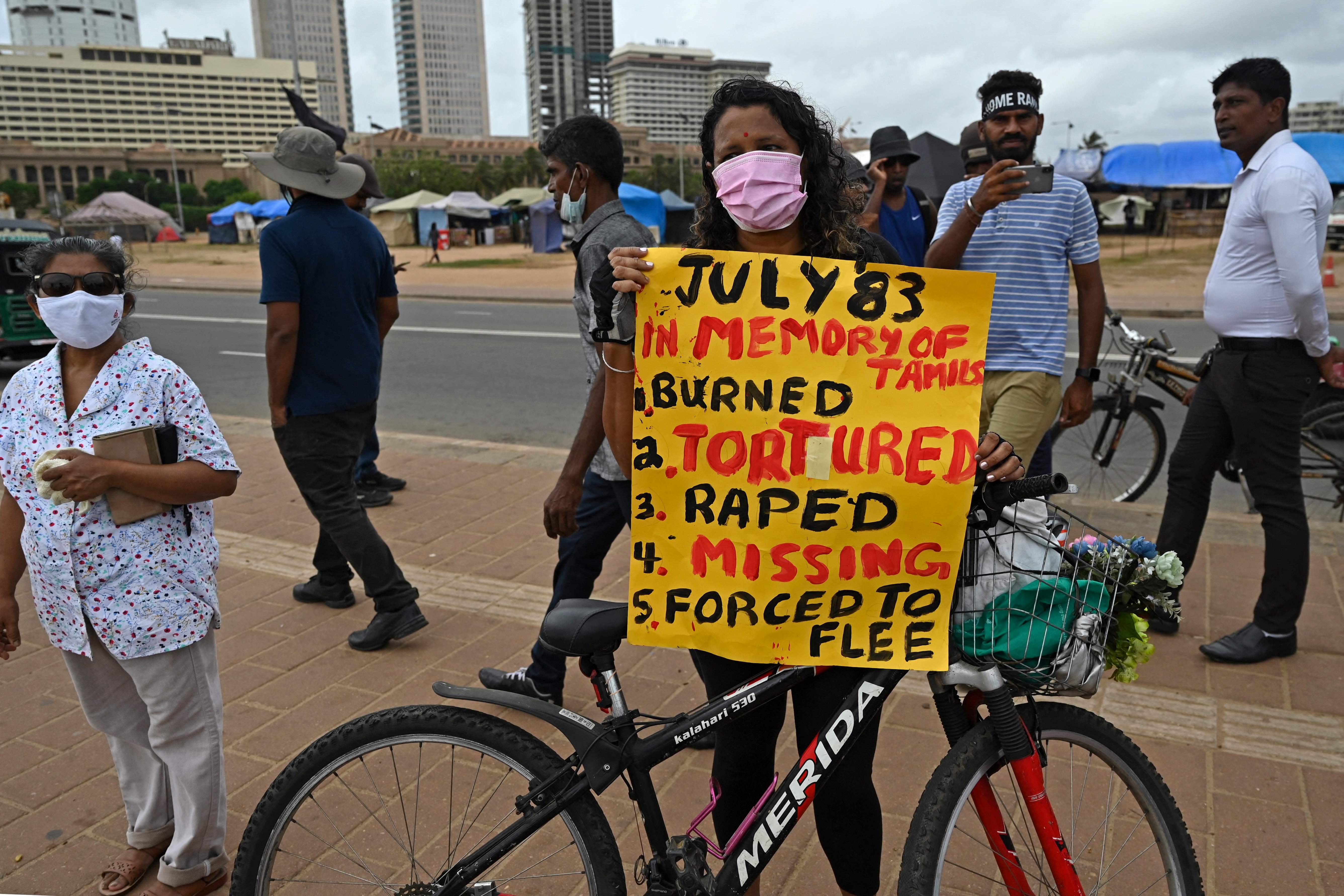 A demonstrator holds a placard during a protest to observe the anniversary of anti-Tamil rioting