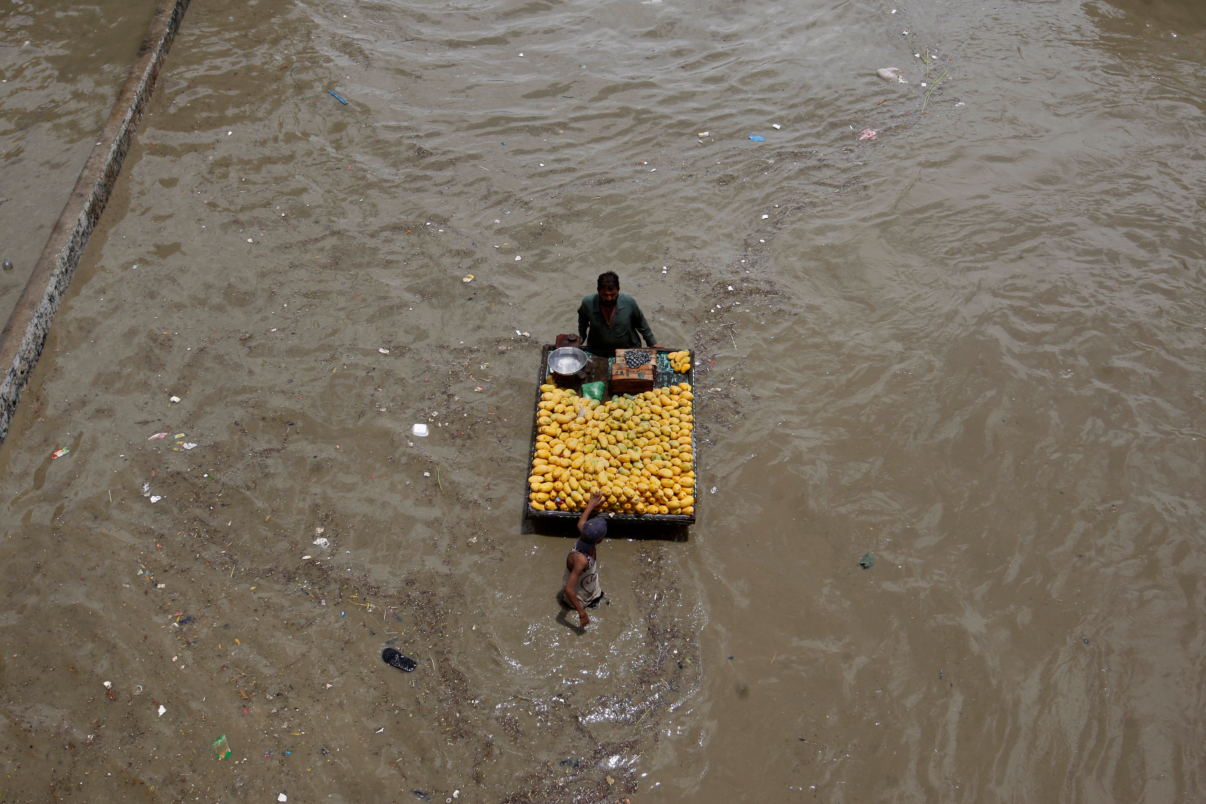 A fruit seller navigates a flooded road after heavy rainfall in Karachi, Pakistan