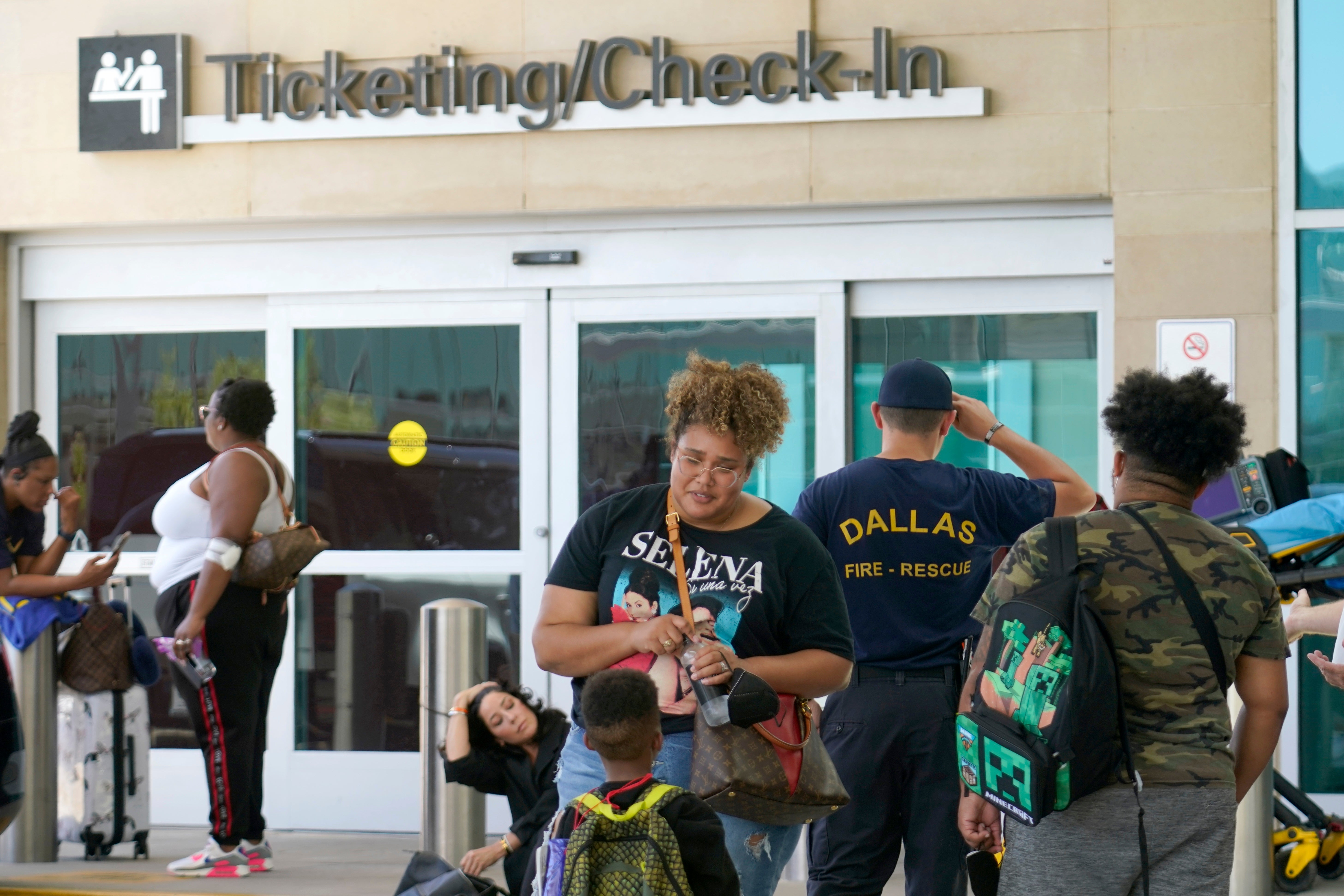 An emergency responder stands amongst travelers outside the ticketing and check in counter at Dallas Love Field in Dallas, Monday, July 25, 2022