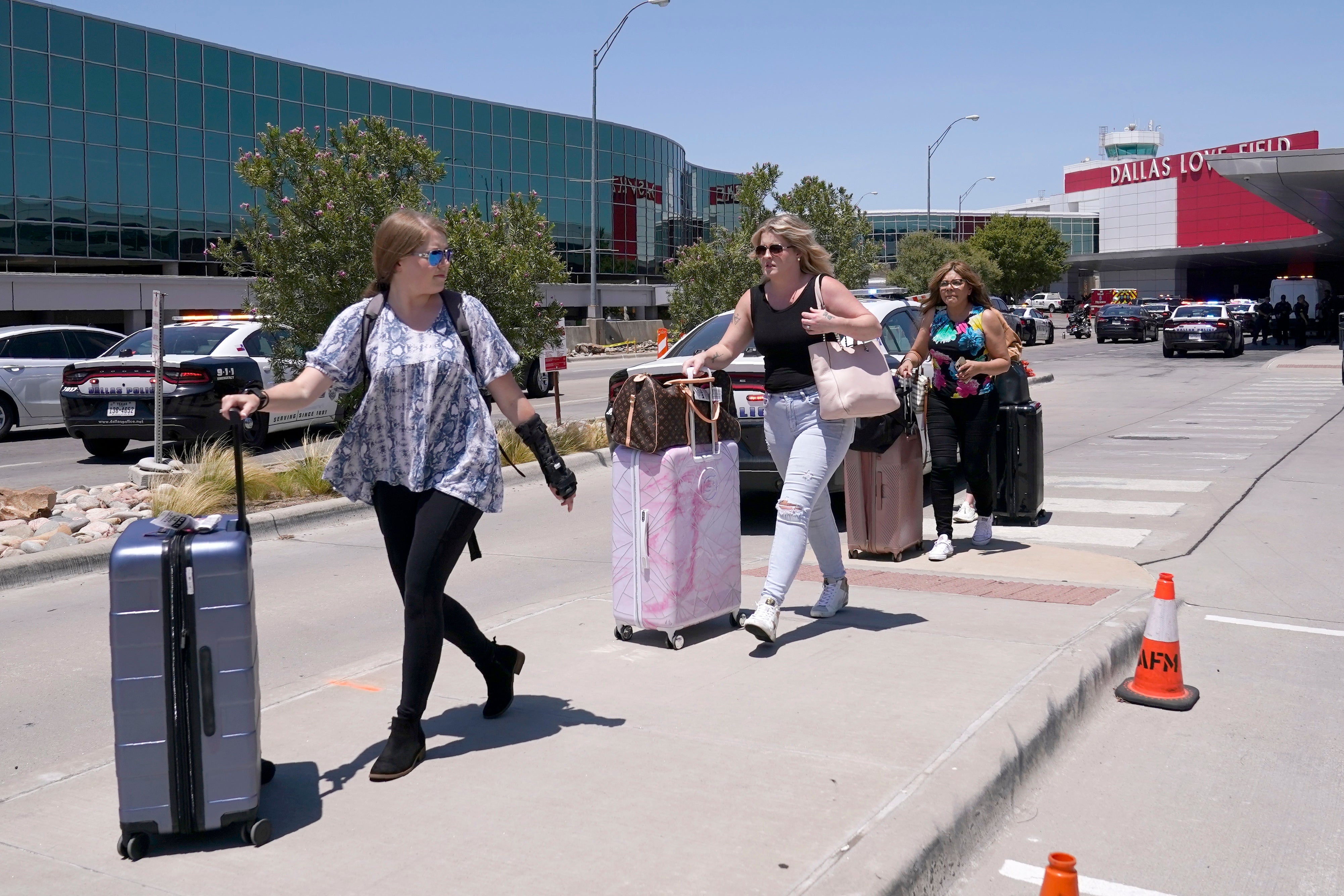 Travelers walk to a parking area outside of Dallas Love Field in Dallas, Monday, July 25, 2022