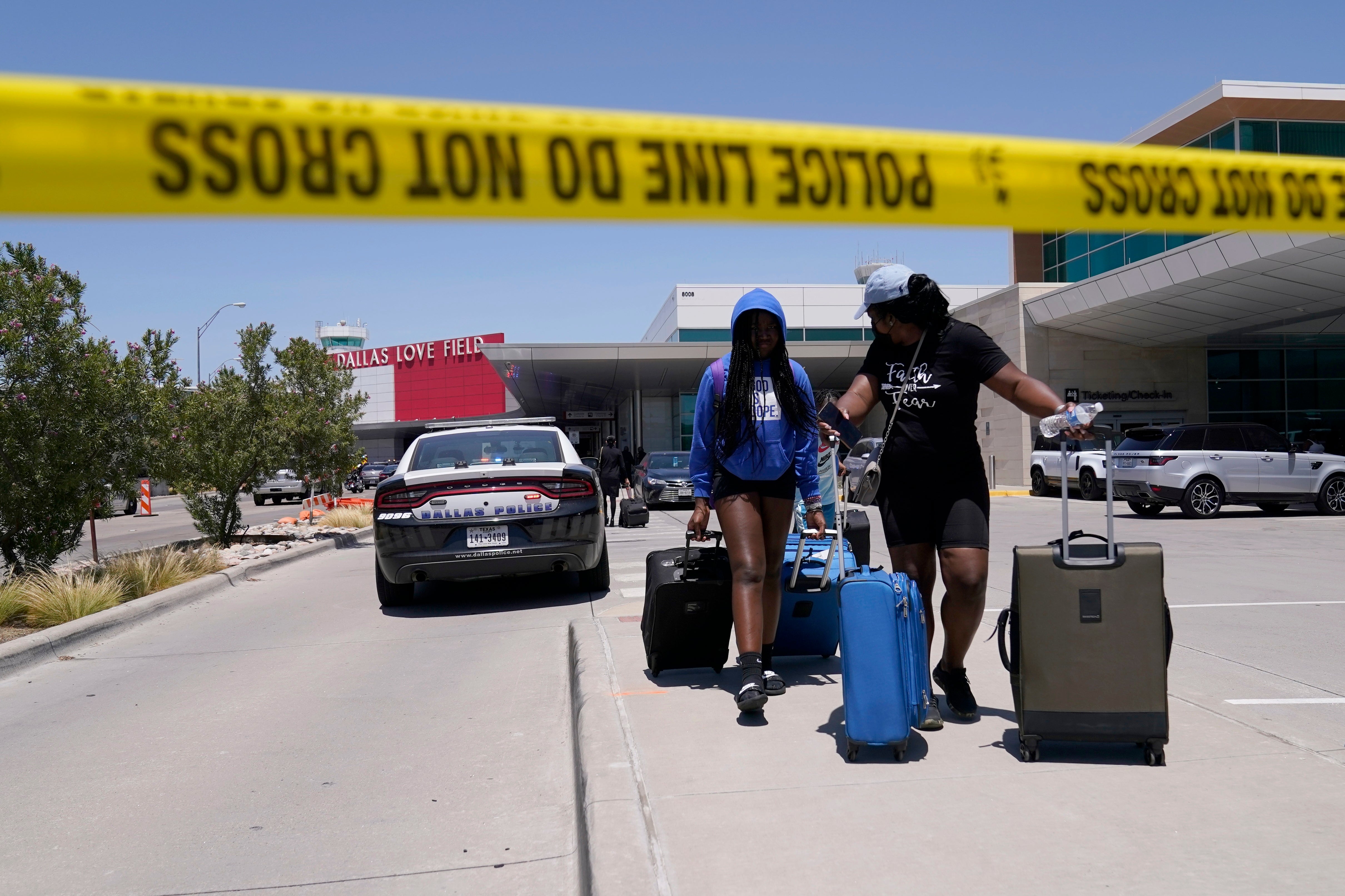 Travelers walk to a parking area outside of Dallas Love Field in Dallas, Monday, July 25, 2022