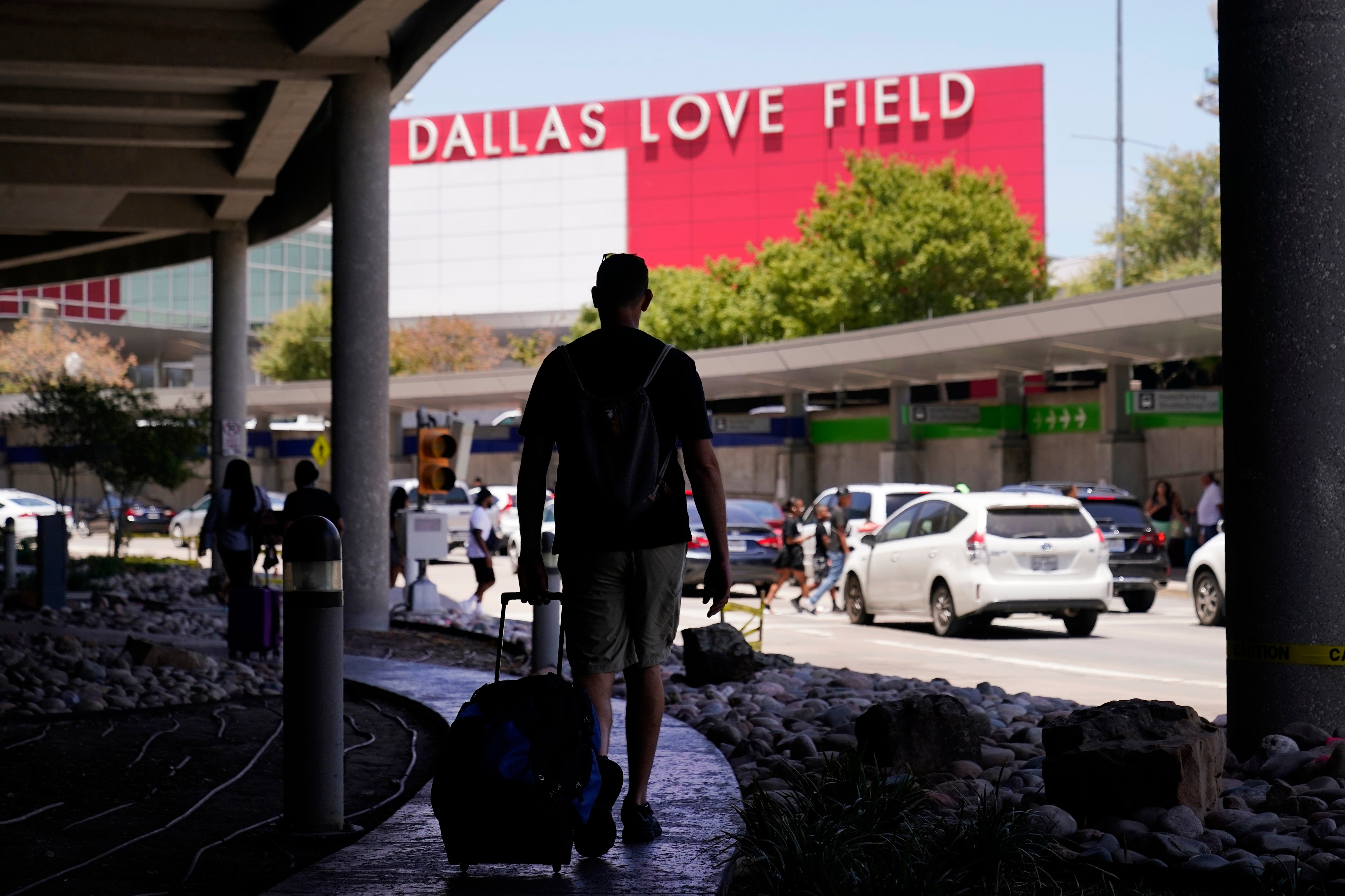 Travelers approach the main entrance at Dallas Love Field in Dallas, Monday, July 25, 2022