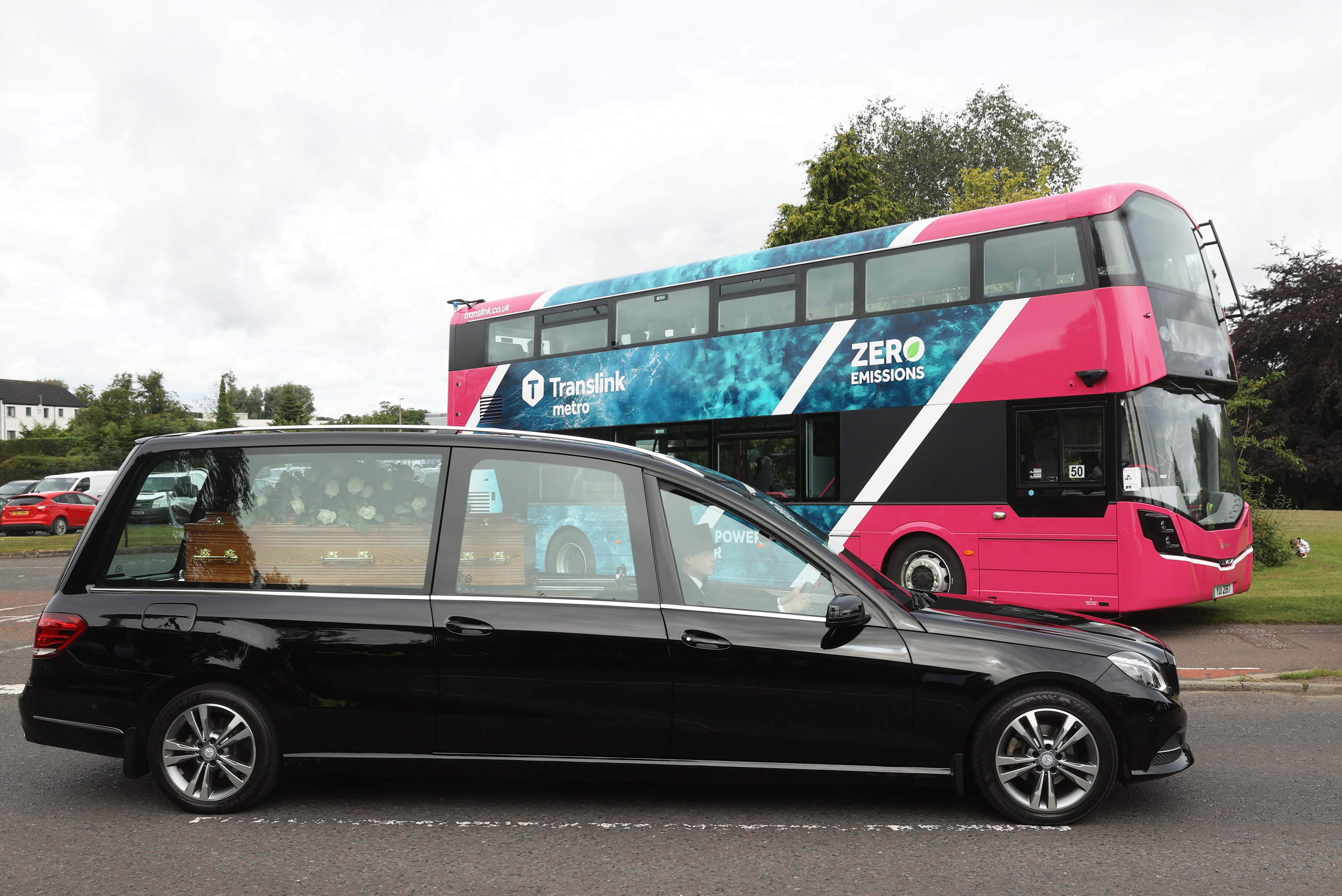 The funeral cortege of the founder of Wrightbus, Sir William Wright, passes a zero-emissions bus outside the factory in Ballymena (Liam McBurney/PA)