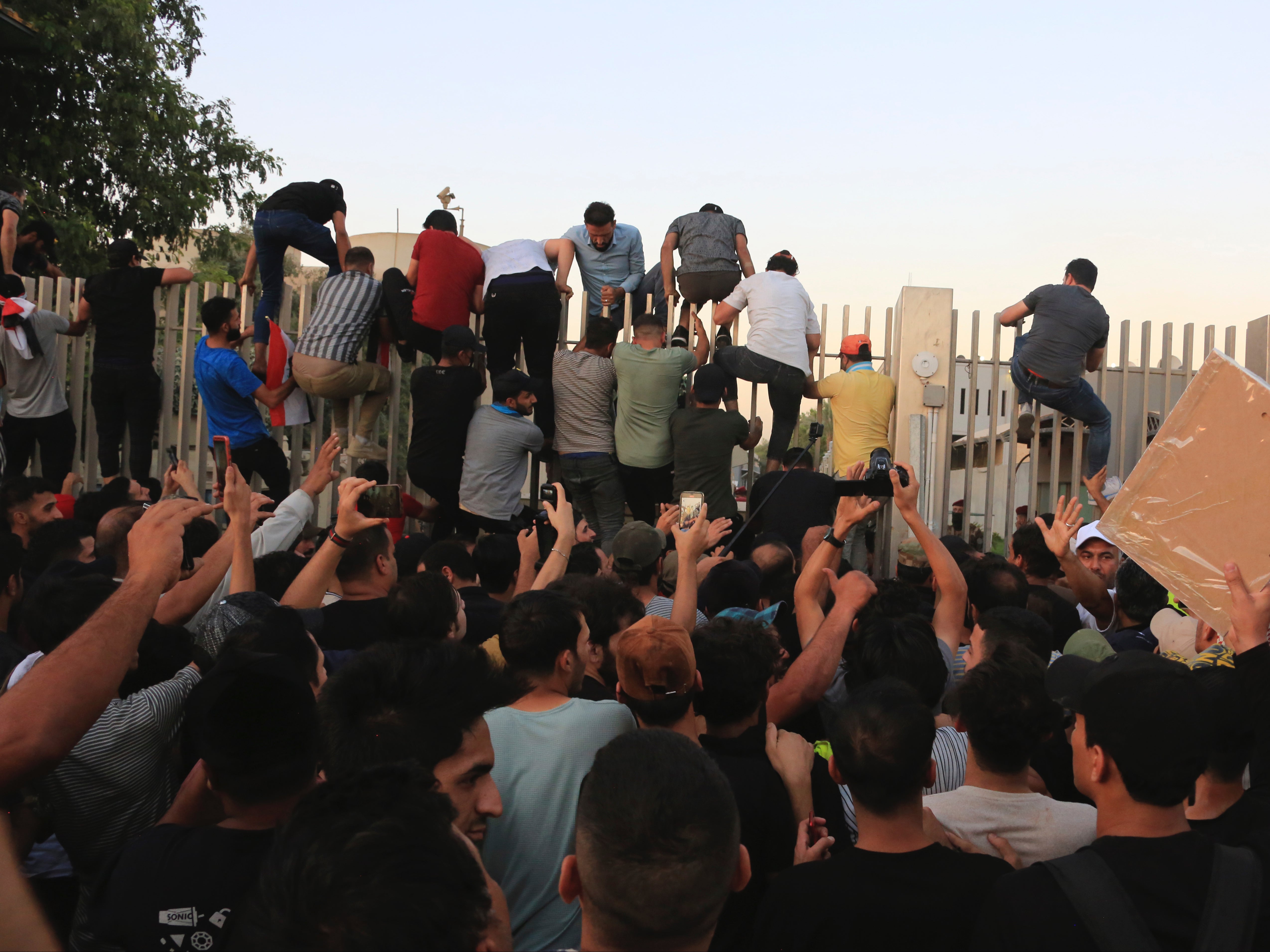 Protesters climbing fences of the Green Zone, where government buildings are based