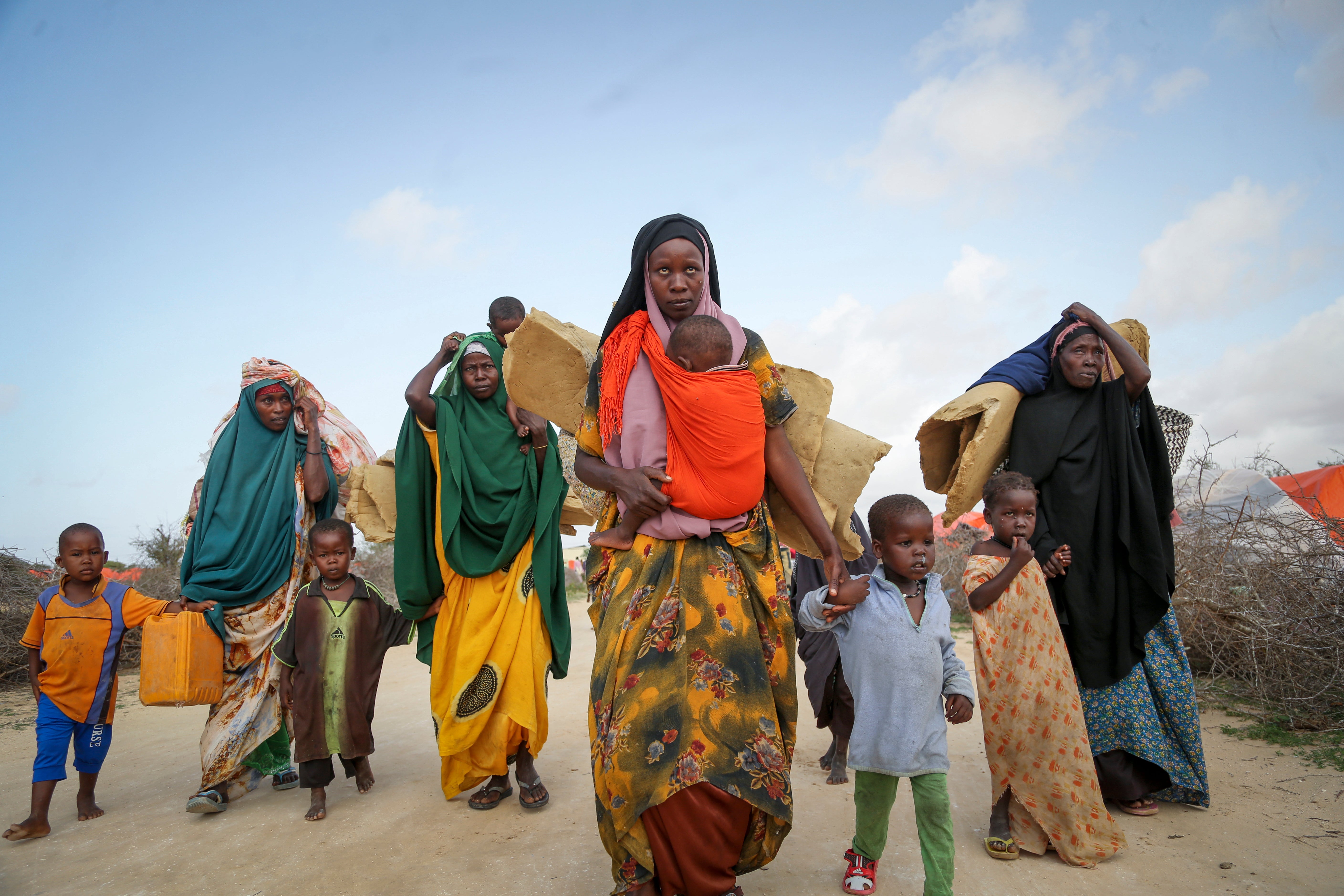 Somalis who fled drought-stricken areas carry their belongings as they arrive at a makeshift camp for the displaced on the outskirts of Mogadishu, Somalia