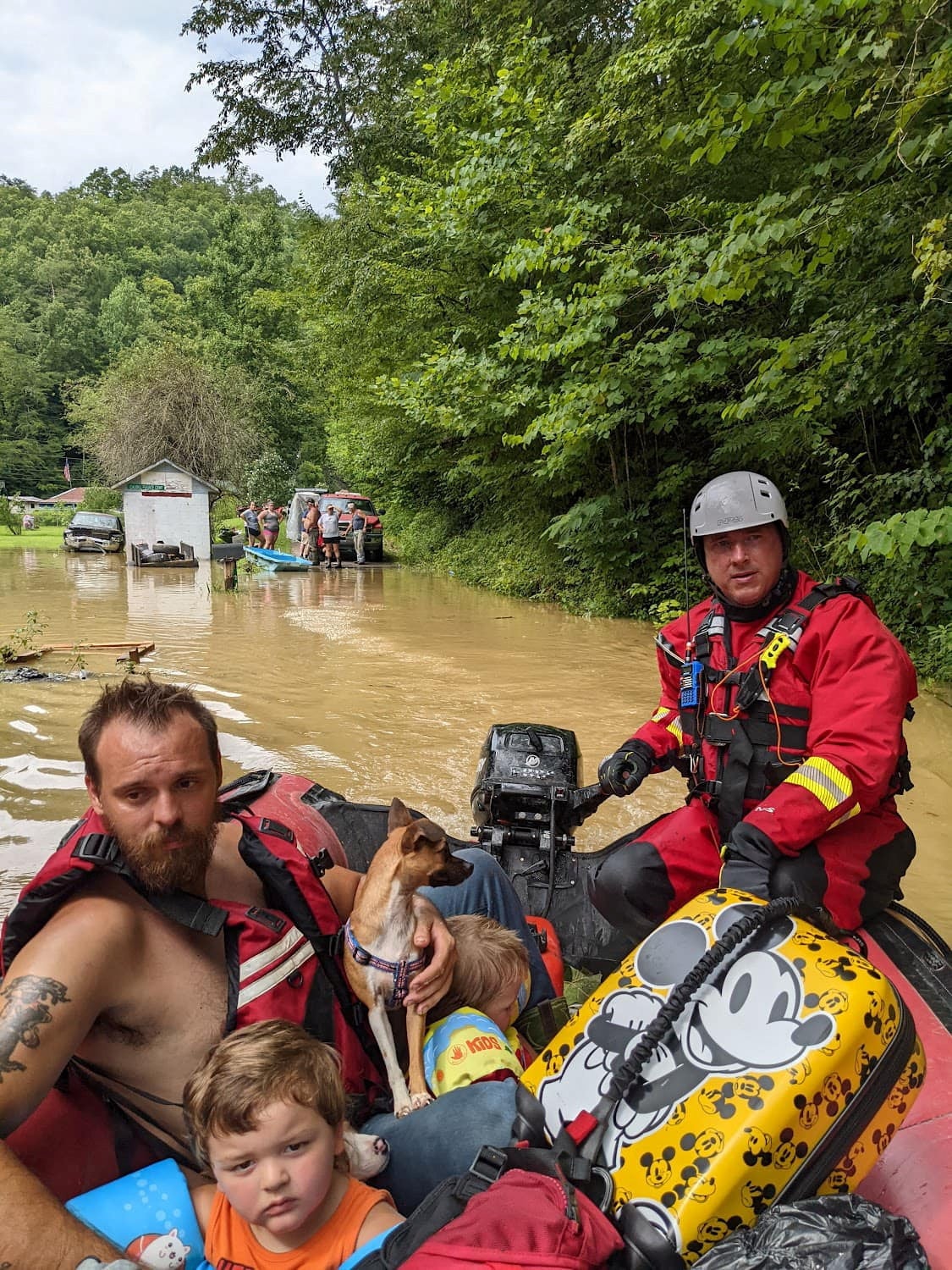 A rescue team member evacuates residents from their homes in a boat through flooded streets in Breathitt County on Thursday