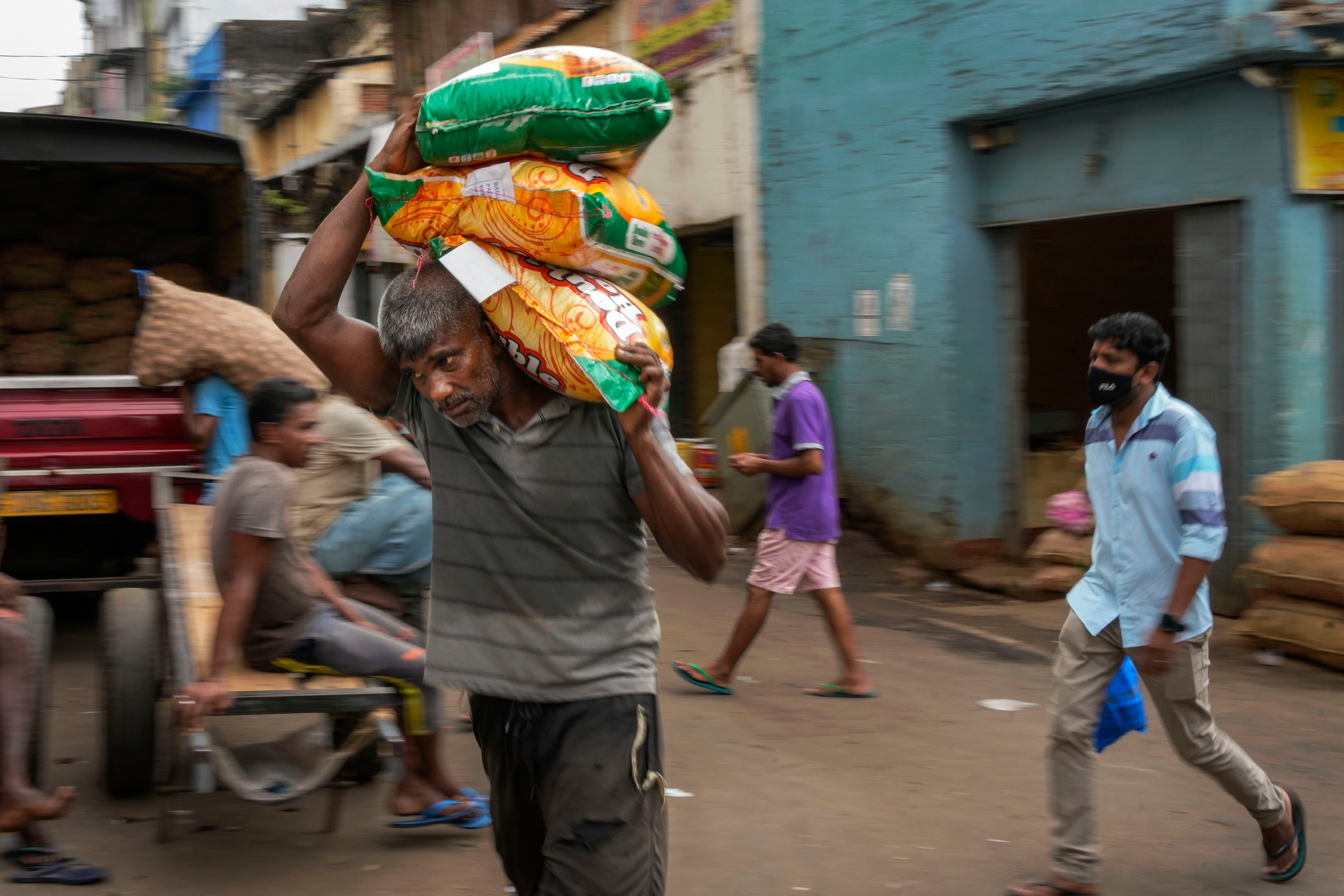 A porter carries sacks of imported food items at a market place in Colombo