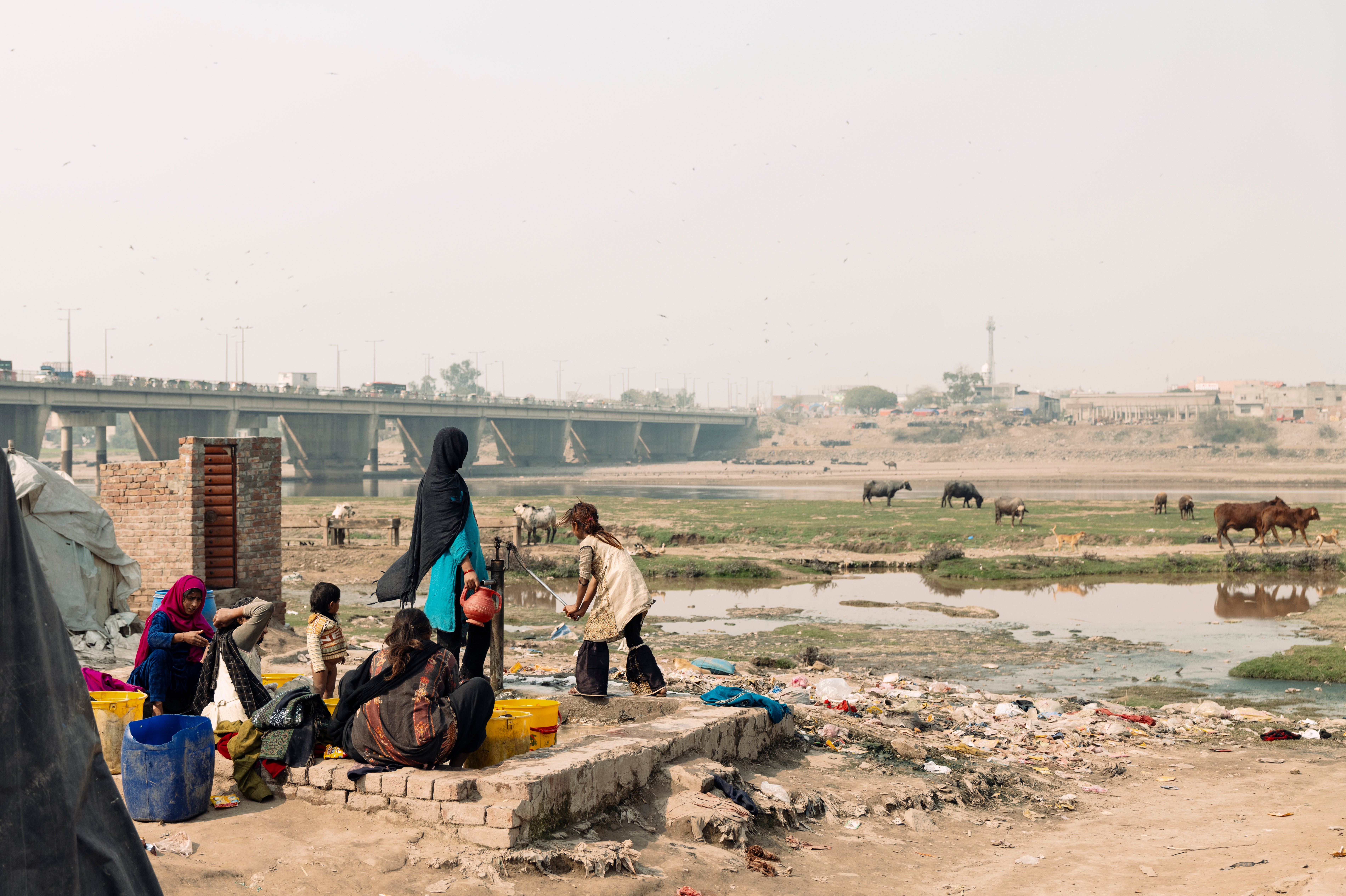 Children helping their parents to wash clothes at the Ravi river slums