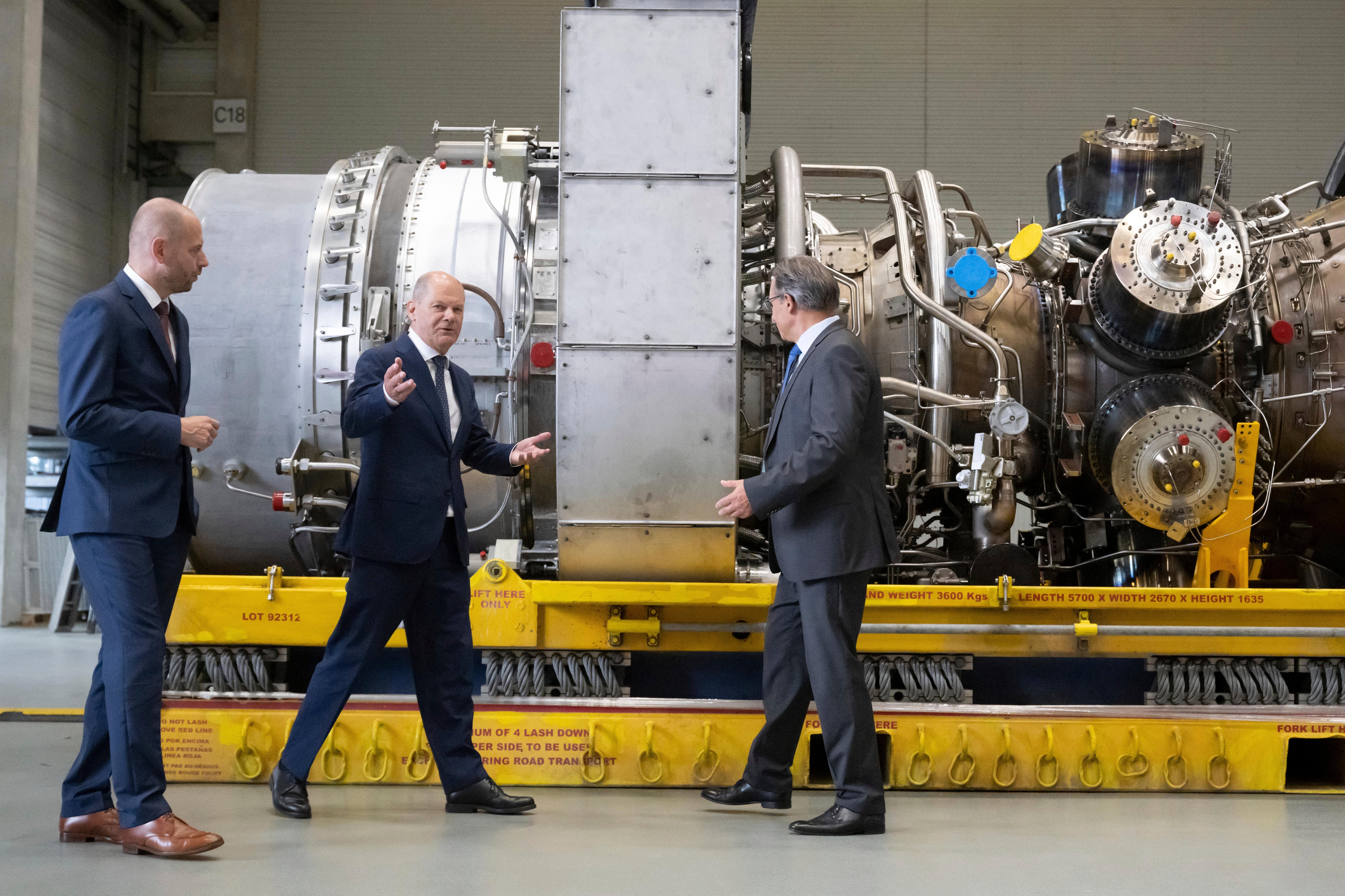 Germany leader Olaf Scholz stands next to a gas turbine