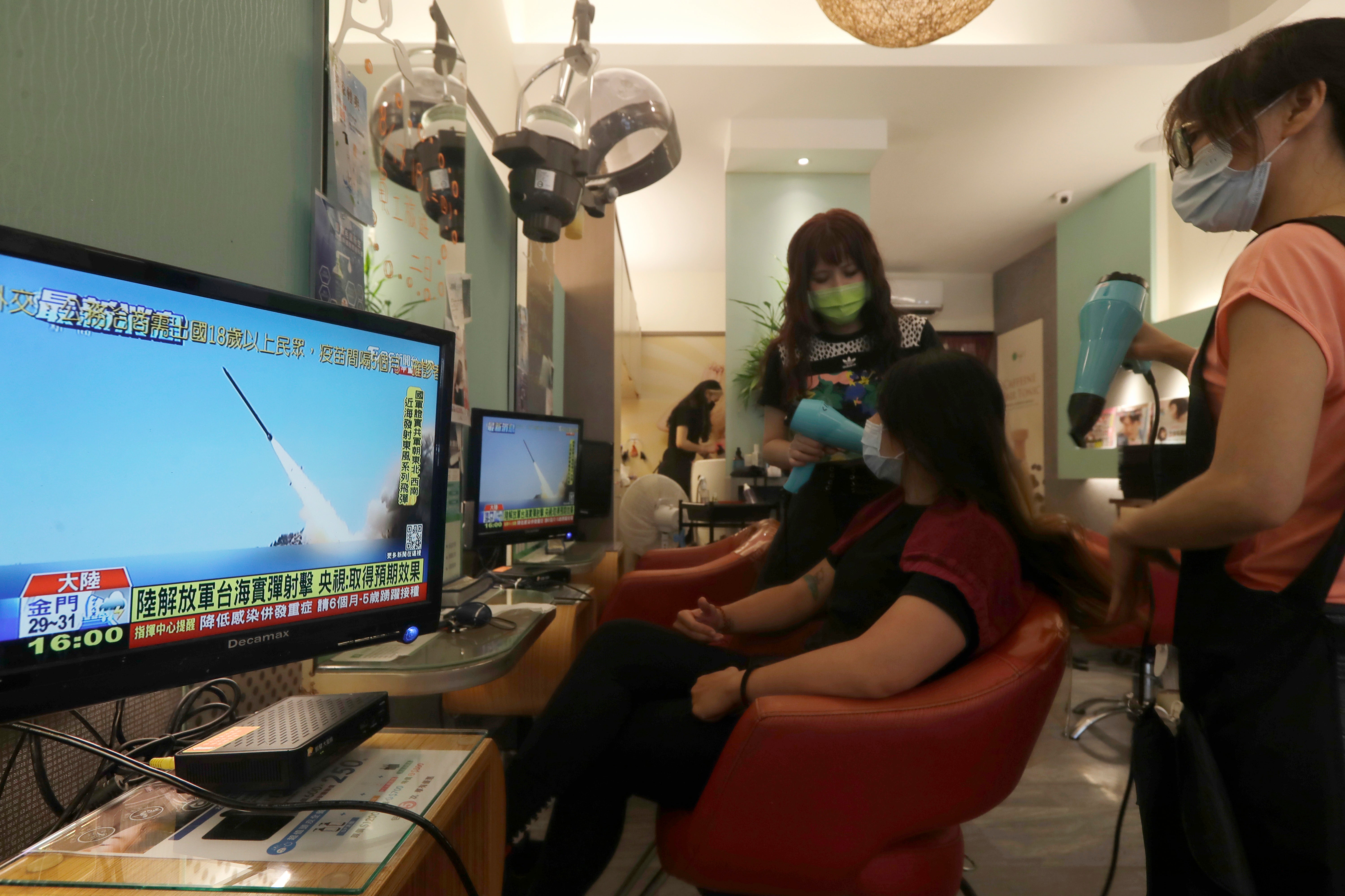 A customer watches a news report on the recent tensions between China and Taiwan, at a beauty salon in Taipei