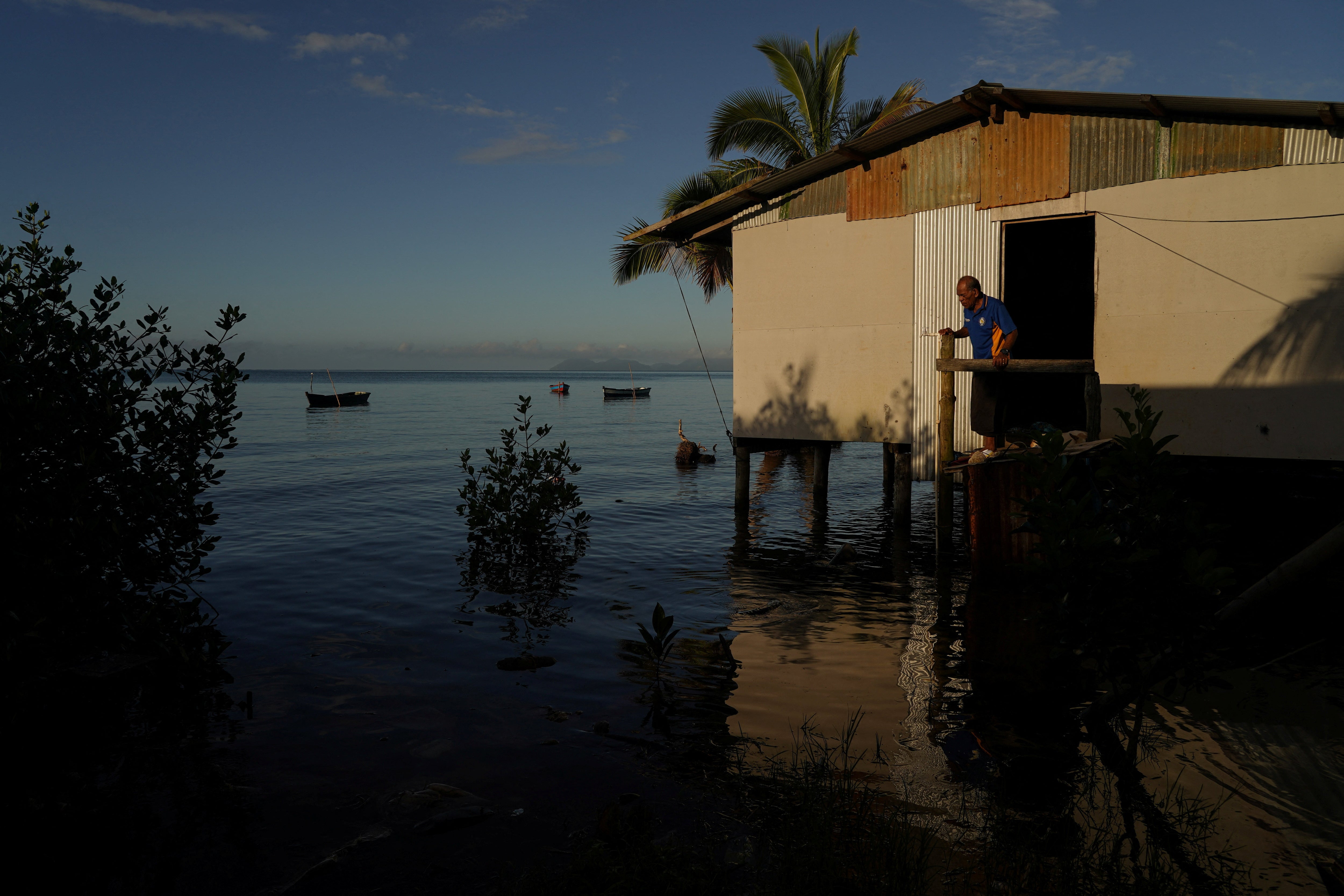 Local resident Rapuma Tuqio, 67, looks out at seawater flooding around his home at high tide in Veivatuloa village, Fiji