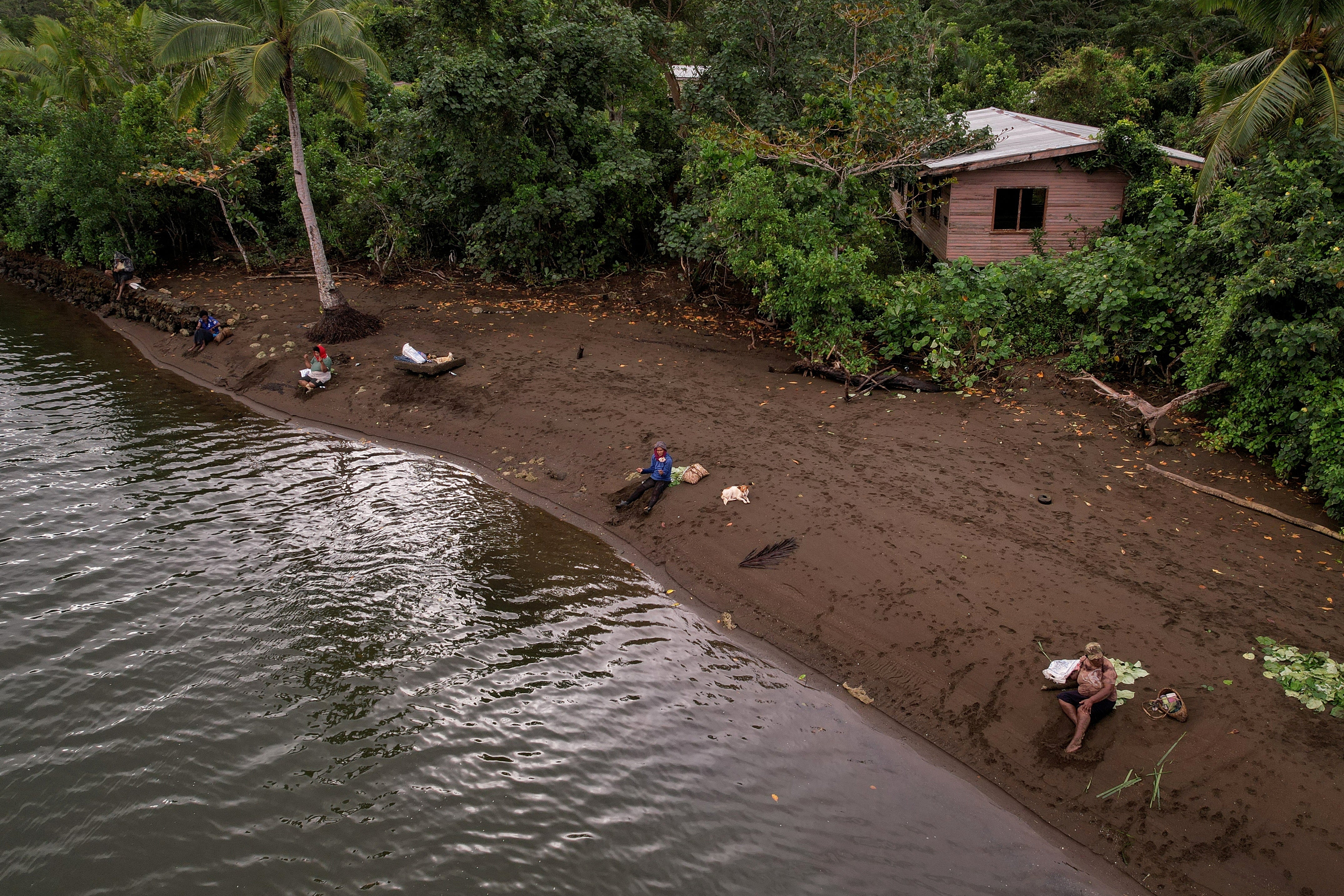 Local residents fish in front of the abandoned site of the old Vunidogoloa village