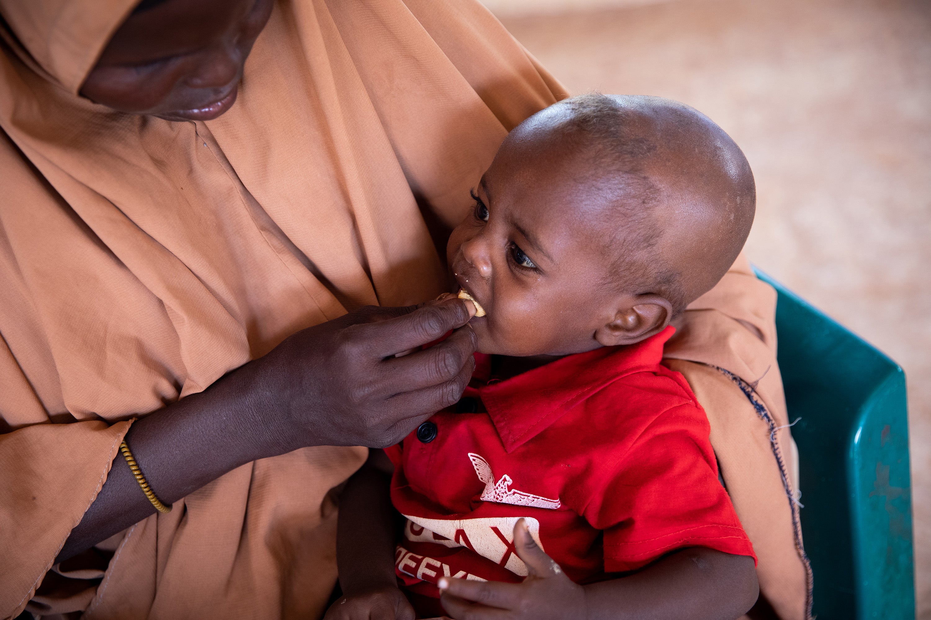 Abdi eats nutritional peanut paste, given to him by his mother