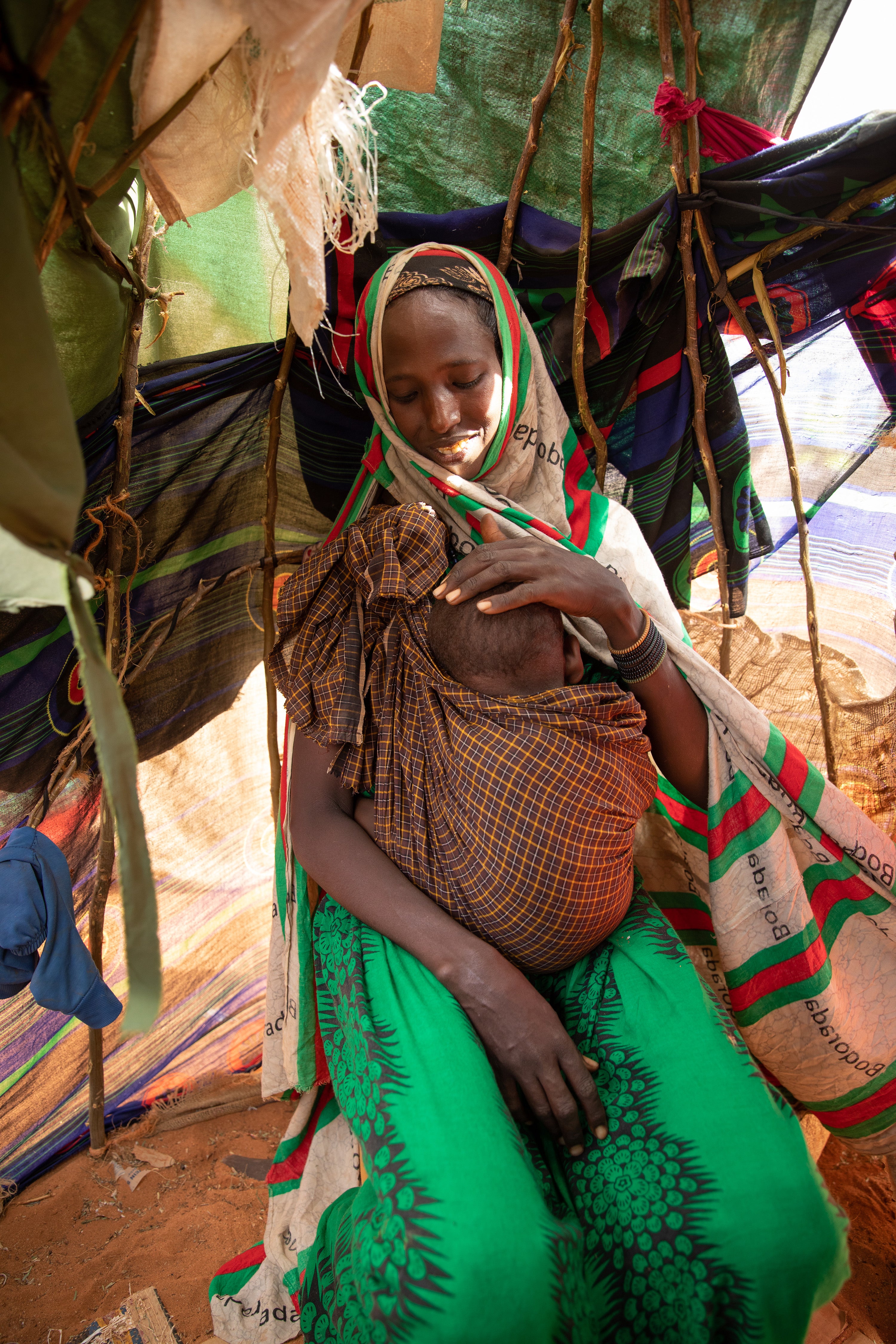 Mido holds Fatun, inside the small shelter they now call home in an internally displaced people (IDP) camp in Kabasa