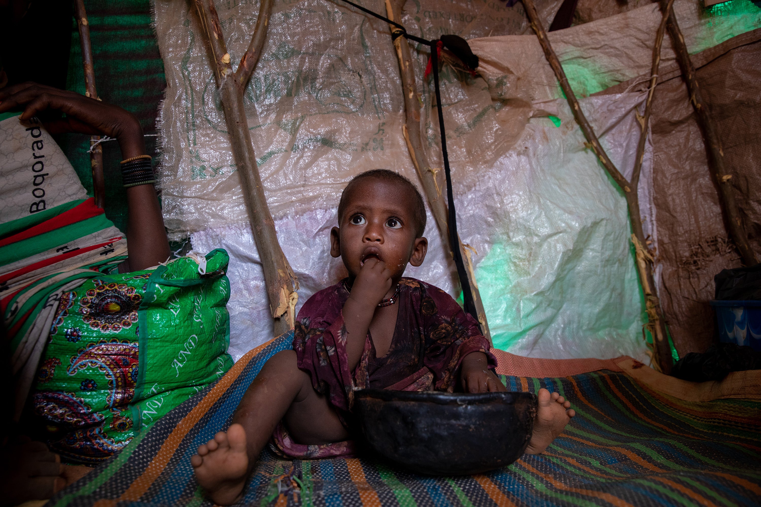 Fatun plays with a bag of WFP supplied super cereal inside the small shelter