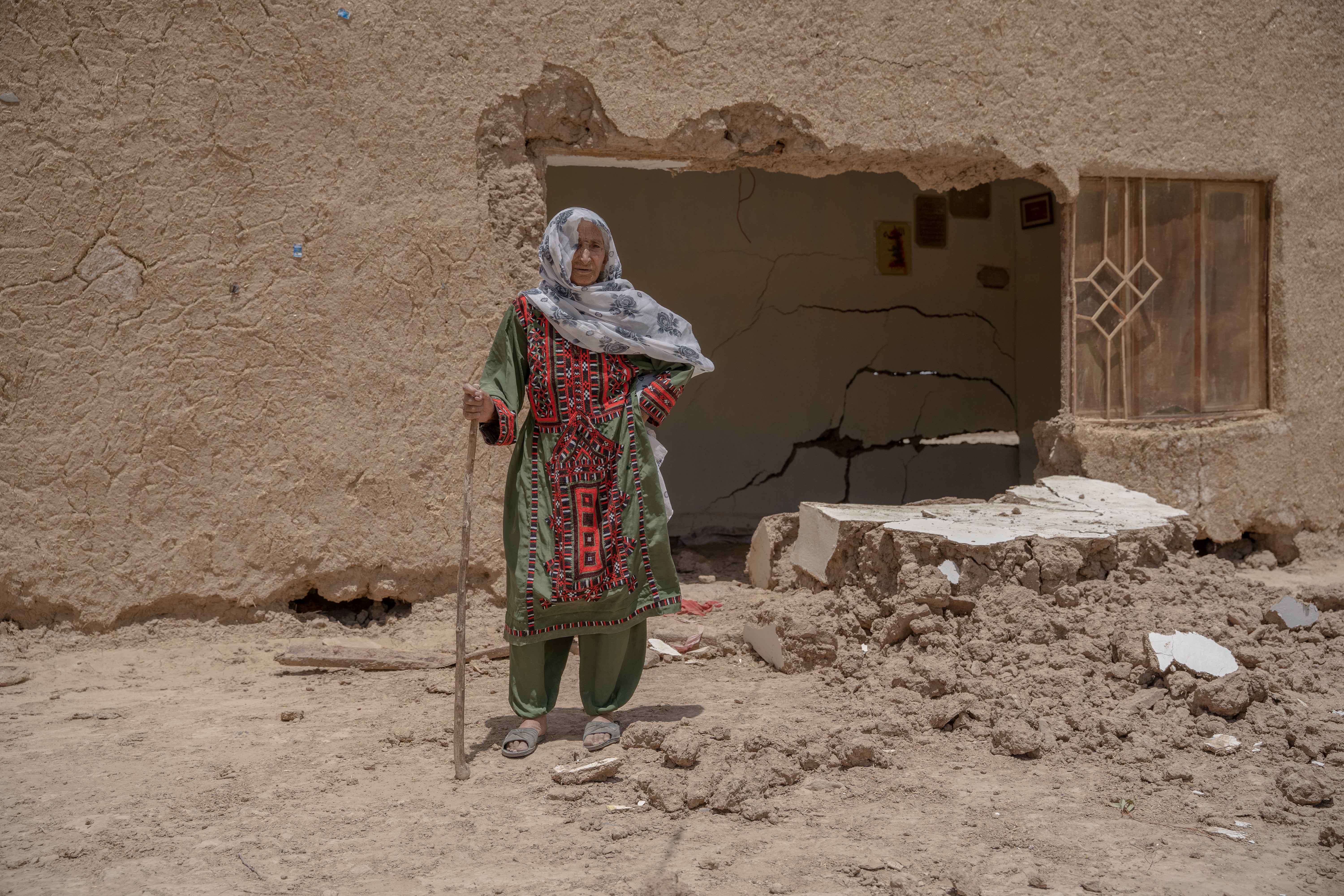 105-year-old Khan Bibi standing outside her damaged house