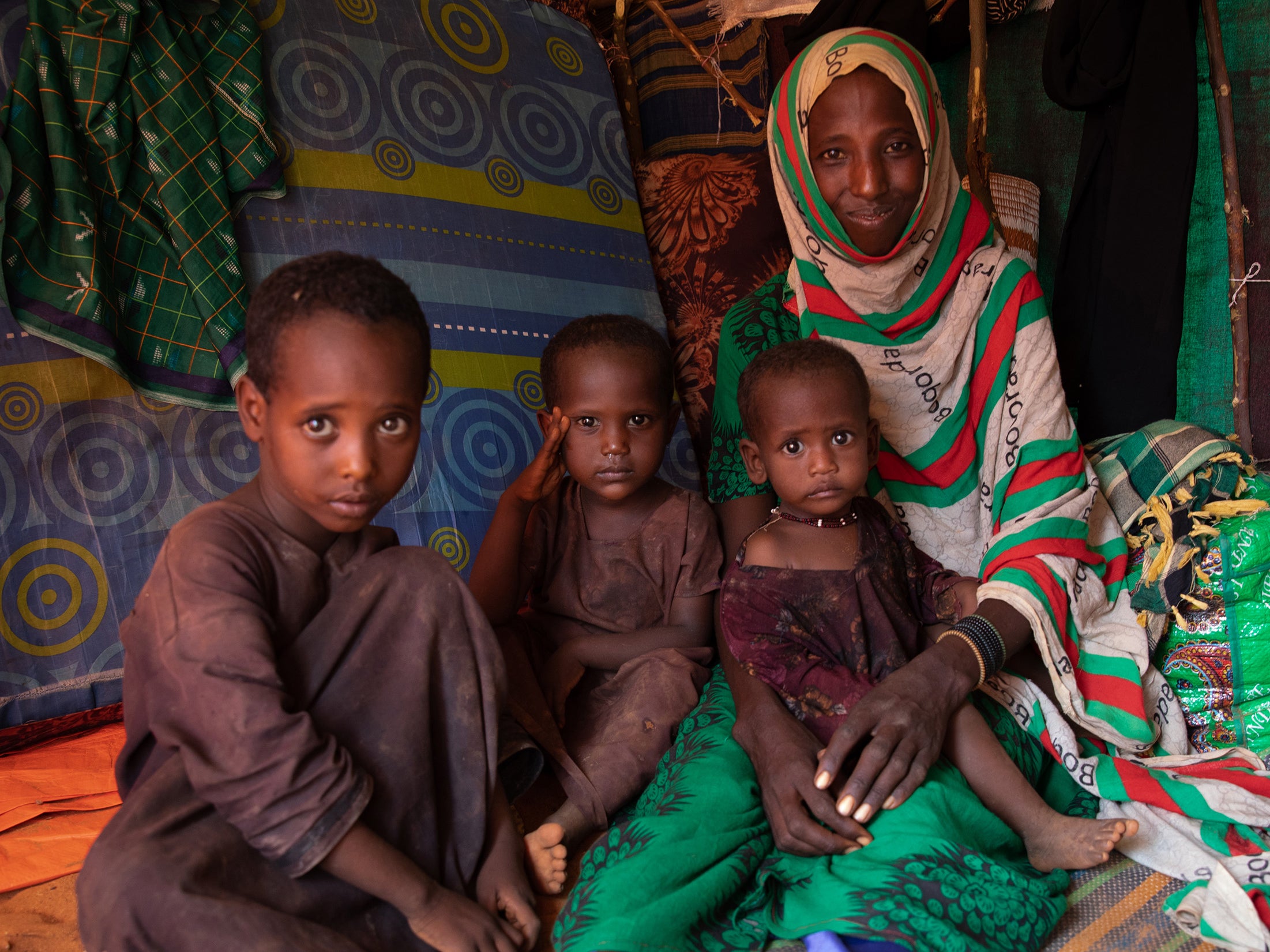 Mido poses with three of her children inside the small shelter they now call home