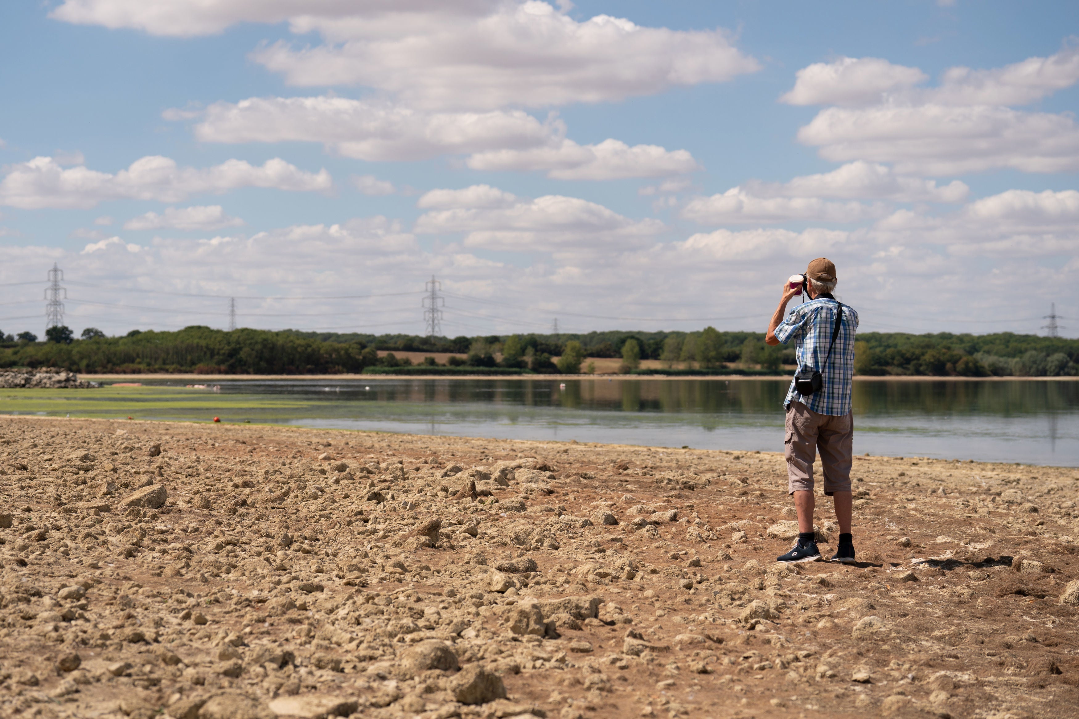 A man stands in the basin of Grafham Water near Huntingdon in Cambridgeshire, where water is receding during prolonged dry weather.