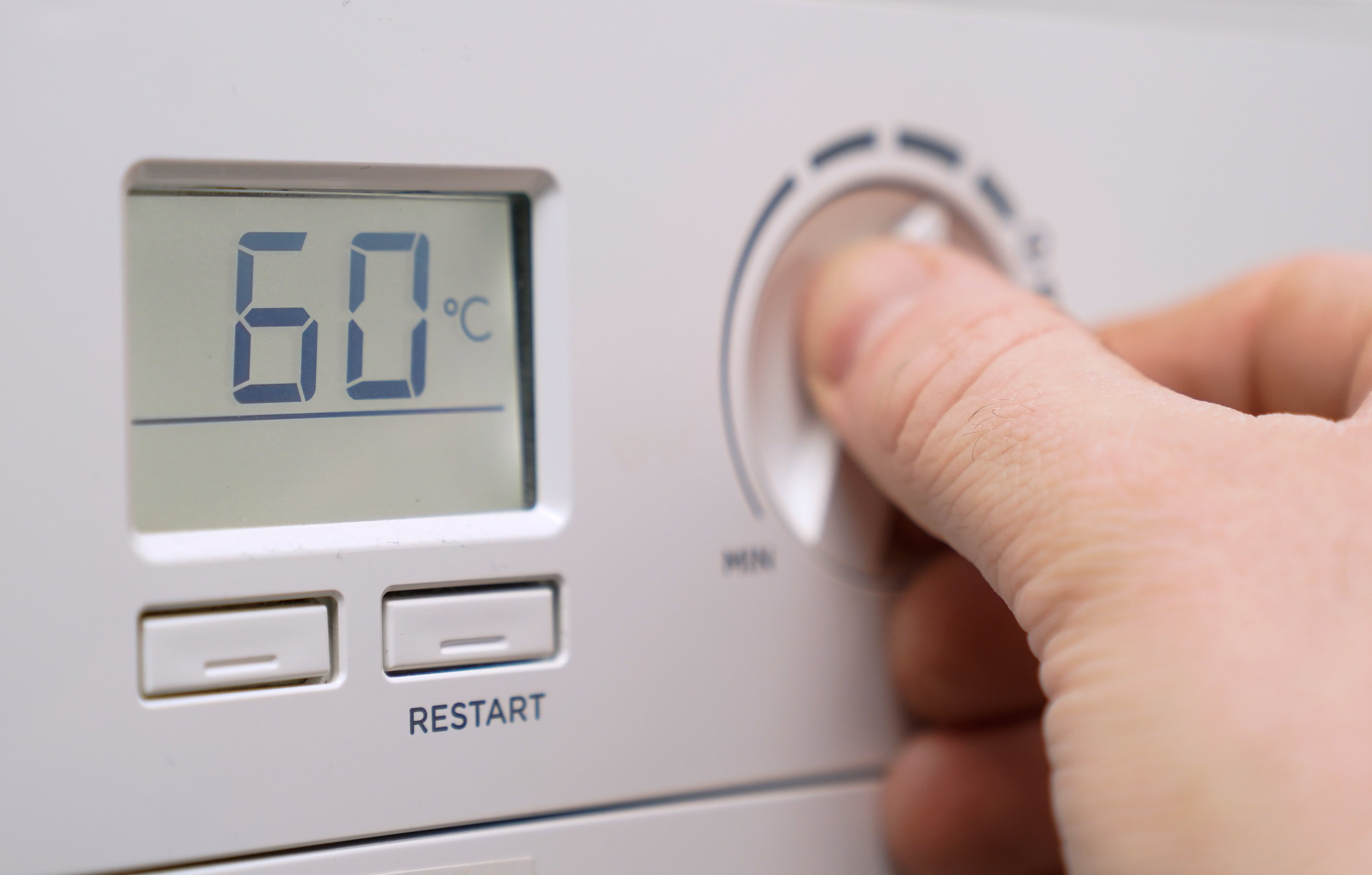 A homeowner turning down the temperature of a gas boiler. (Andrew Matthews/PA)