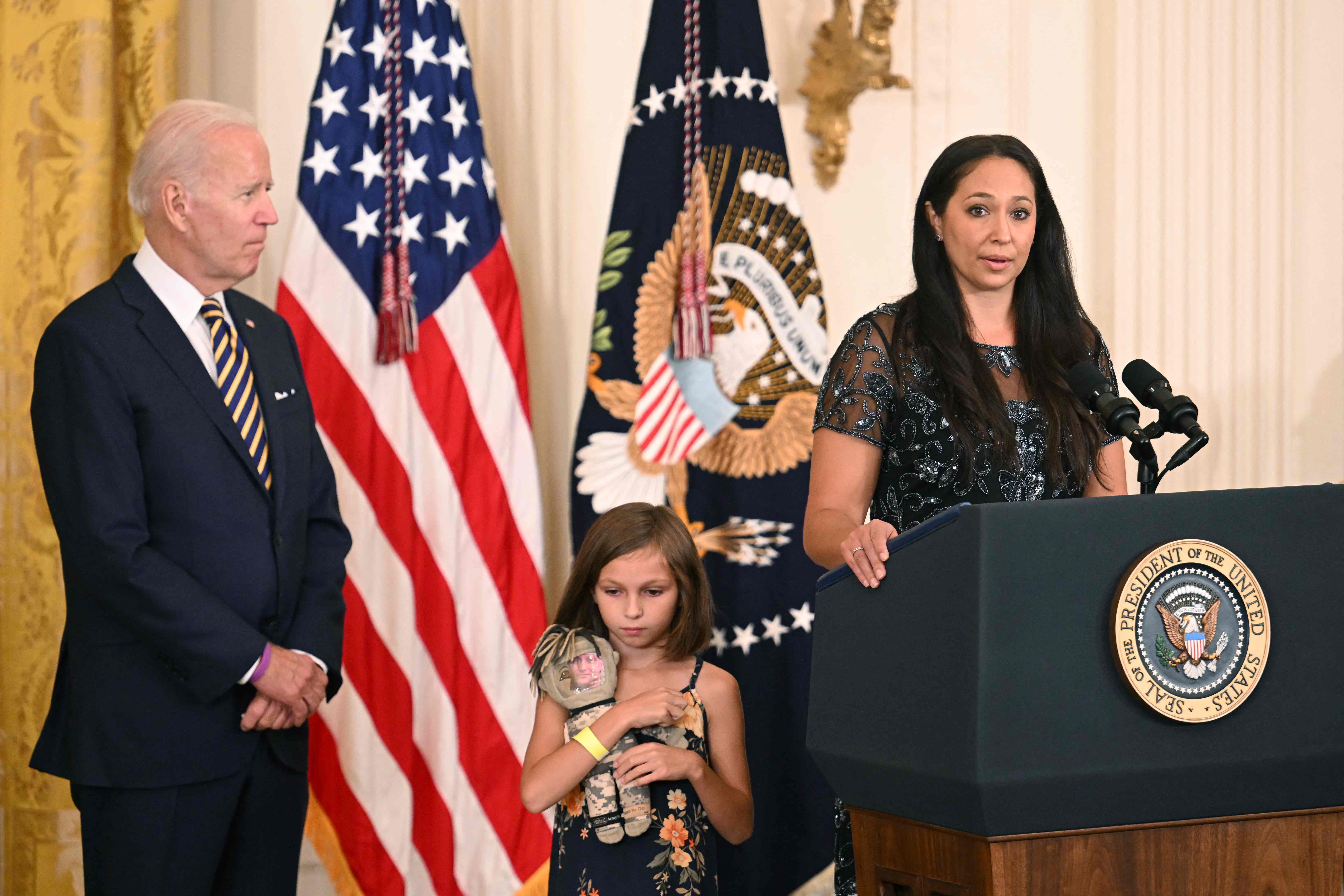 President Joe Biden looks on as Danielle Robinson, wife of Sgt First Class Heath Robinson, speaks during a signing ceremony for the PACT Act of 2022