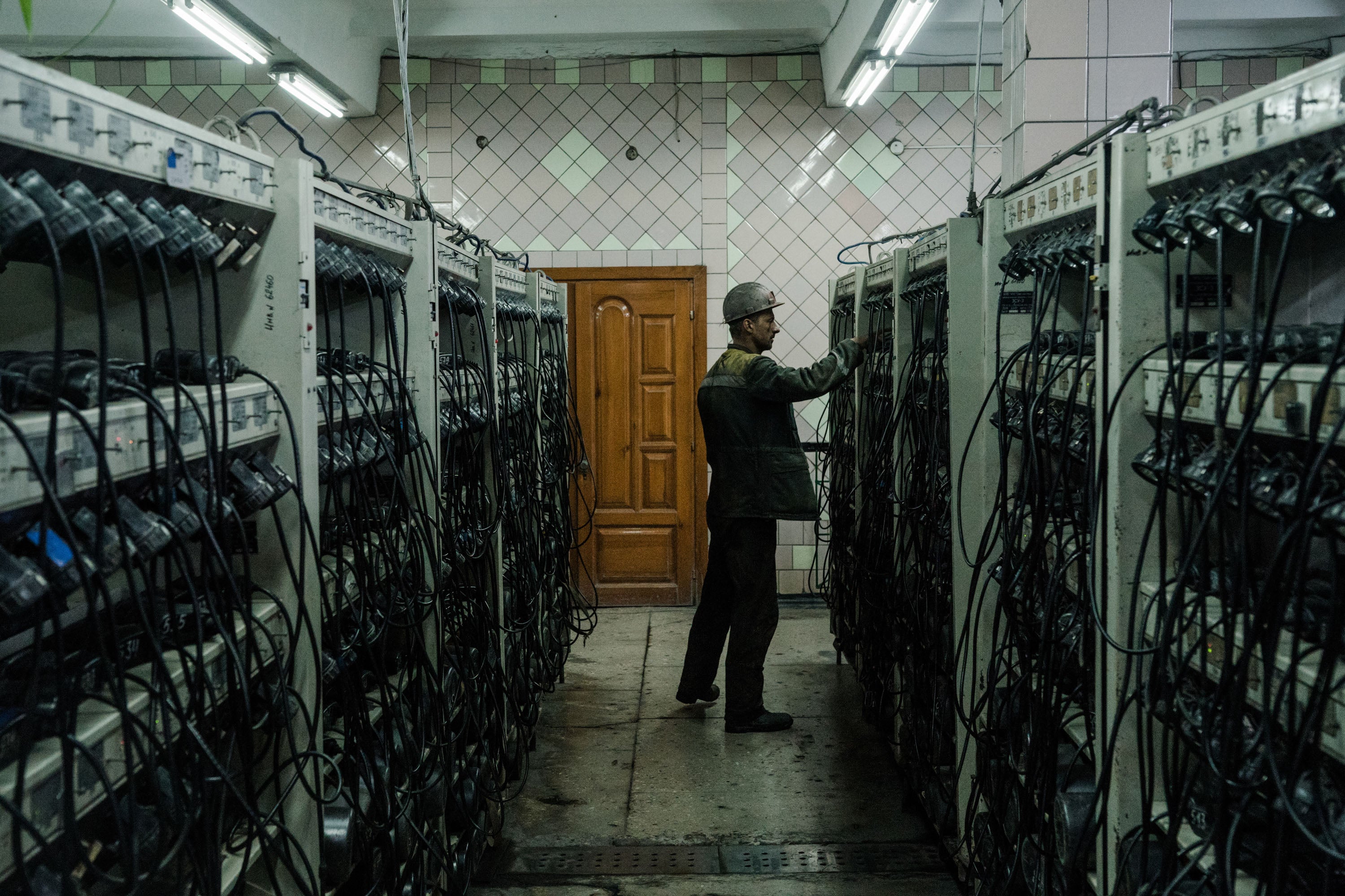 A coal miner stands among rows of equipment during a shift change at a site in Ukraine's Donbas region