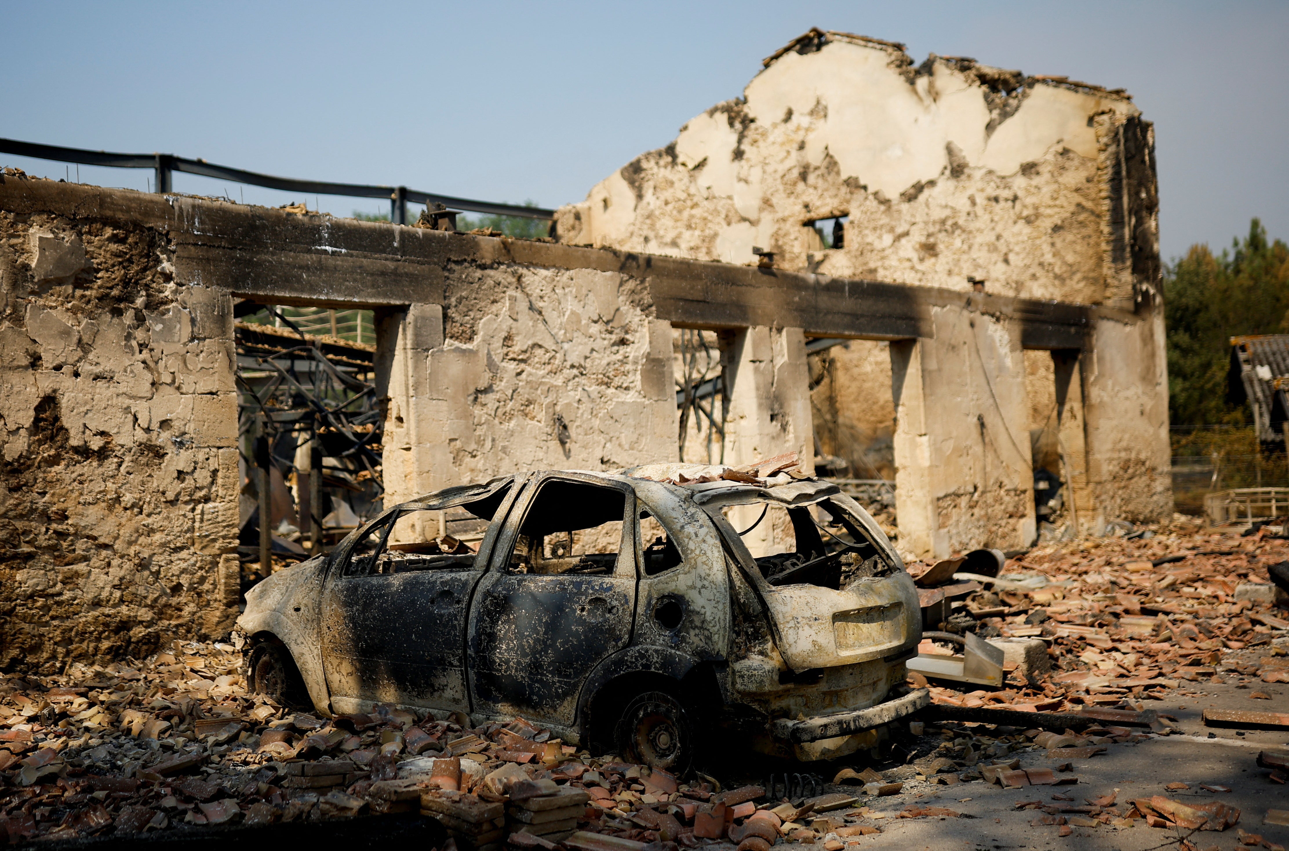 A view of a house and a car destroyed by fire in Belin-Beliet, as wildfires continue to spread in the Gironde region of southwestern France