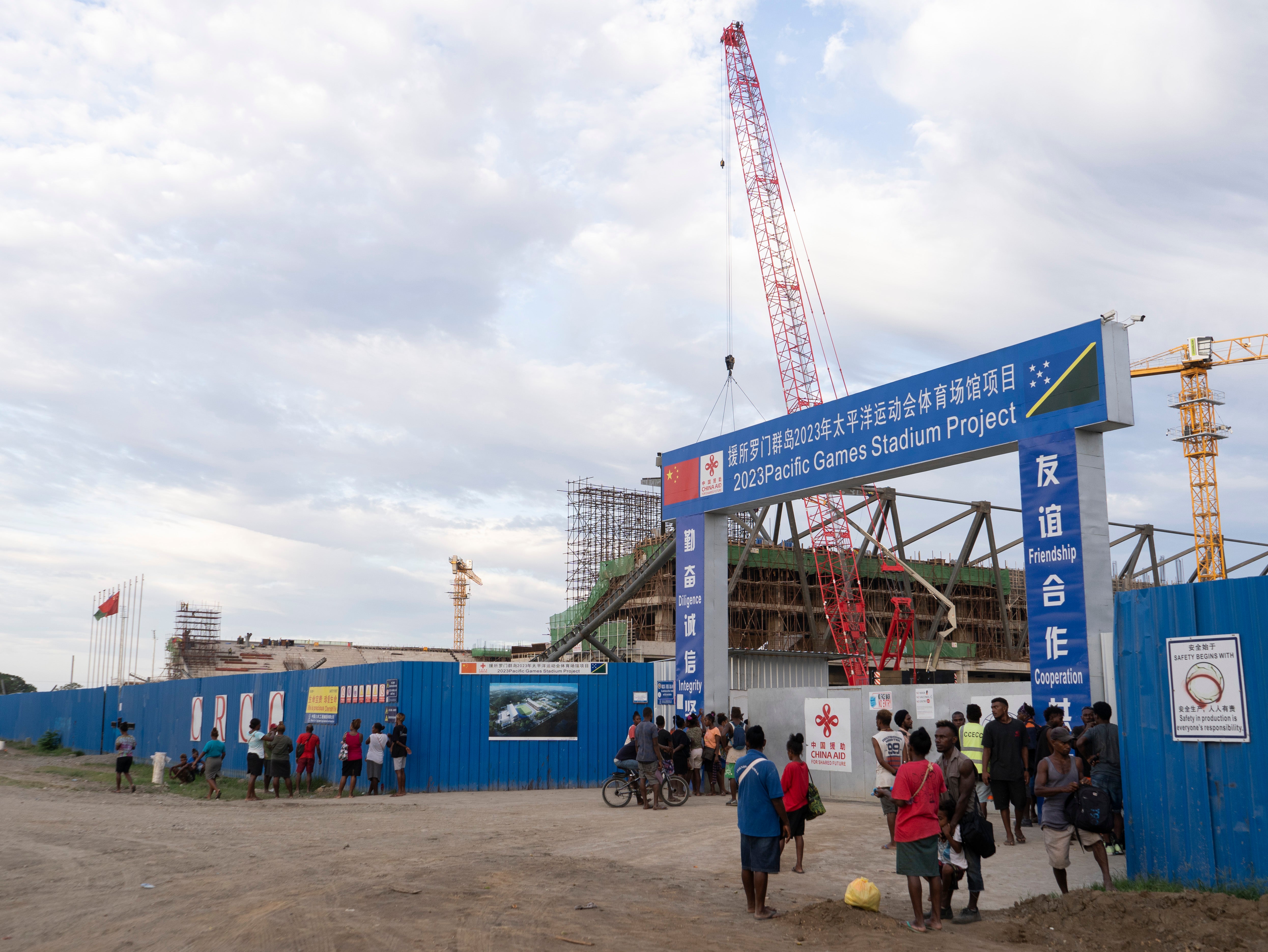 Construction workers, some accompanied by relatives, wait to get paid