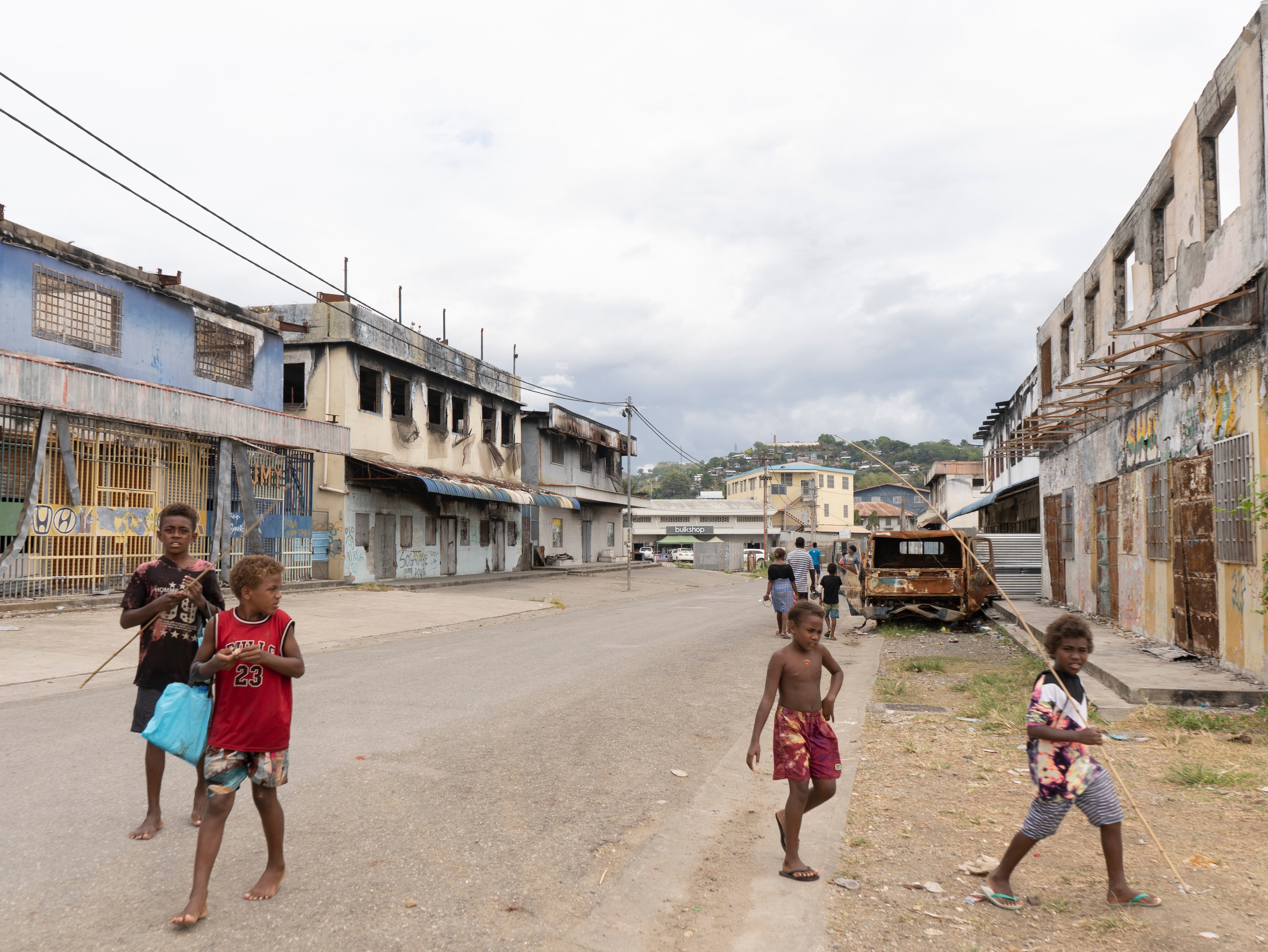 Children traverse riot-scarred Chinatown on their way to fish in Honiara