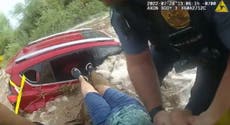 Footage shows police pull trapped woman from submerged car amid flooding