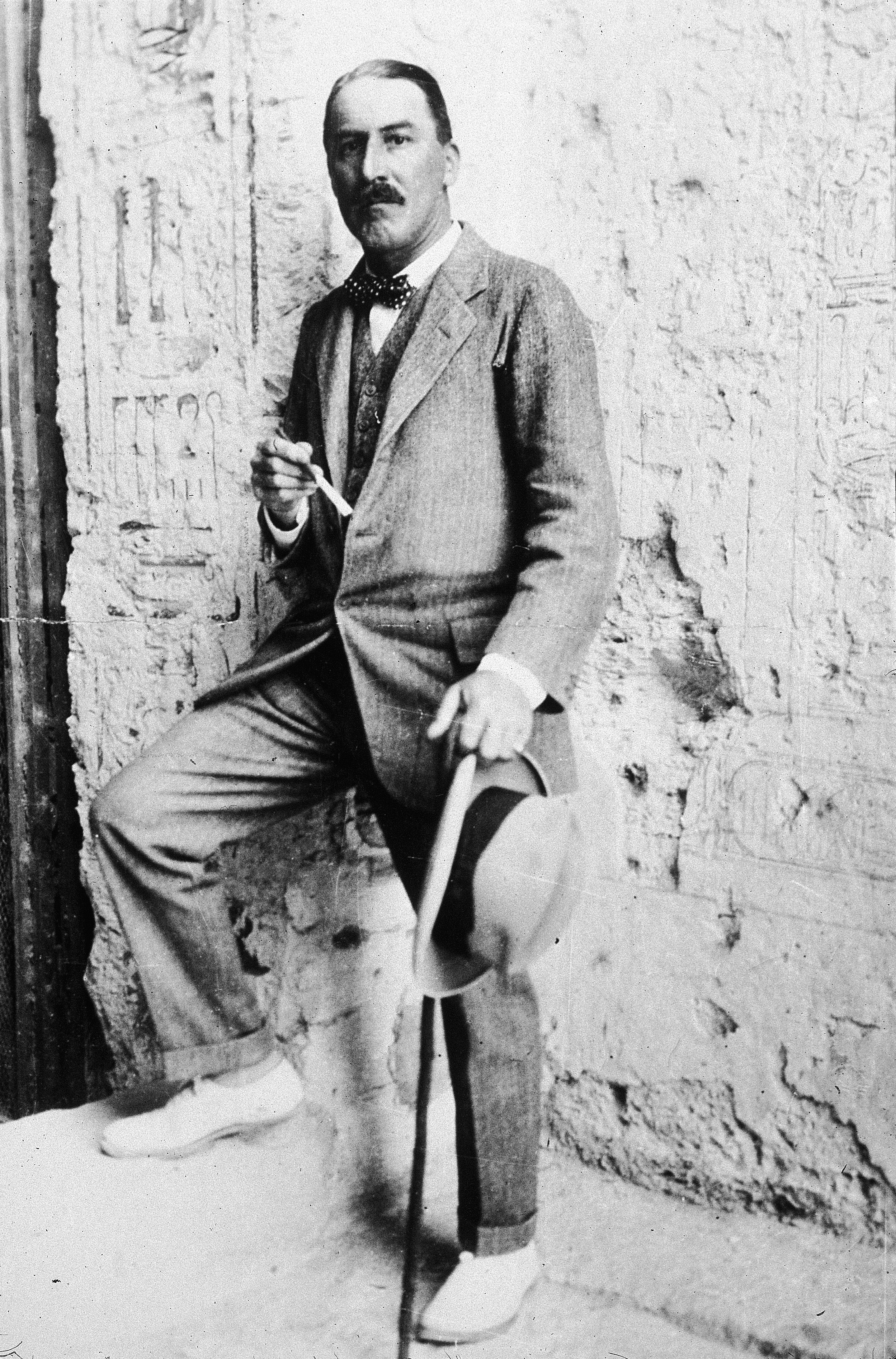 British Egyptologist Howard Carter stands with one foot up on a step at the entrance to an Egyptian archaeological site in 1923