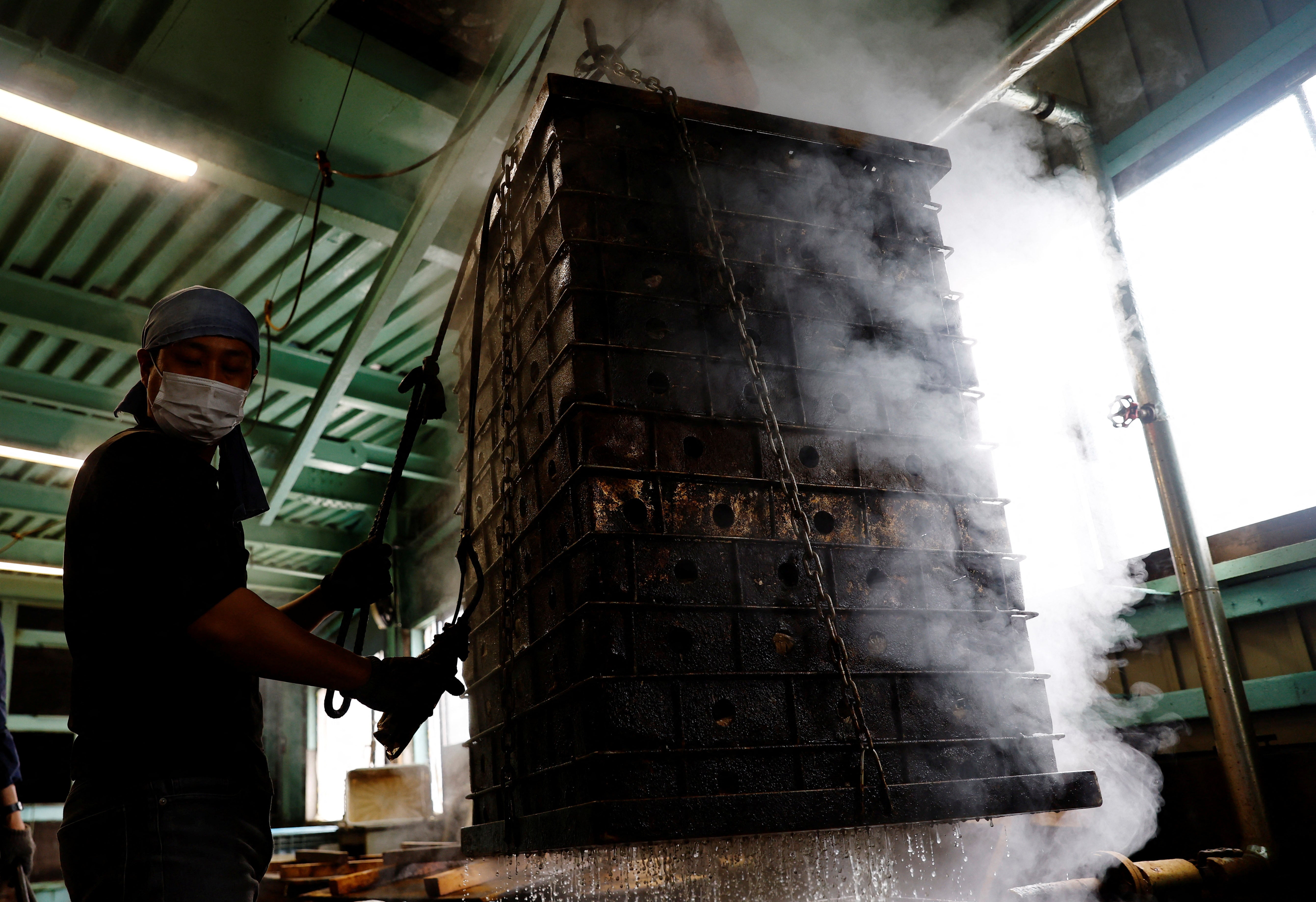 A worker carries baskets containing boiled fillets of katsuo to make katsuobushi at the Takeuchi Ltd factory