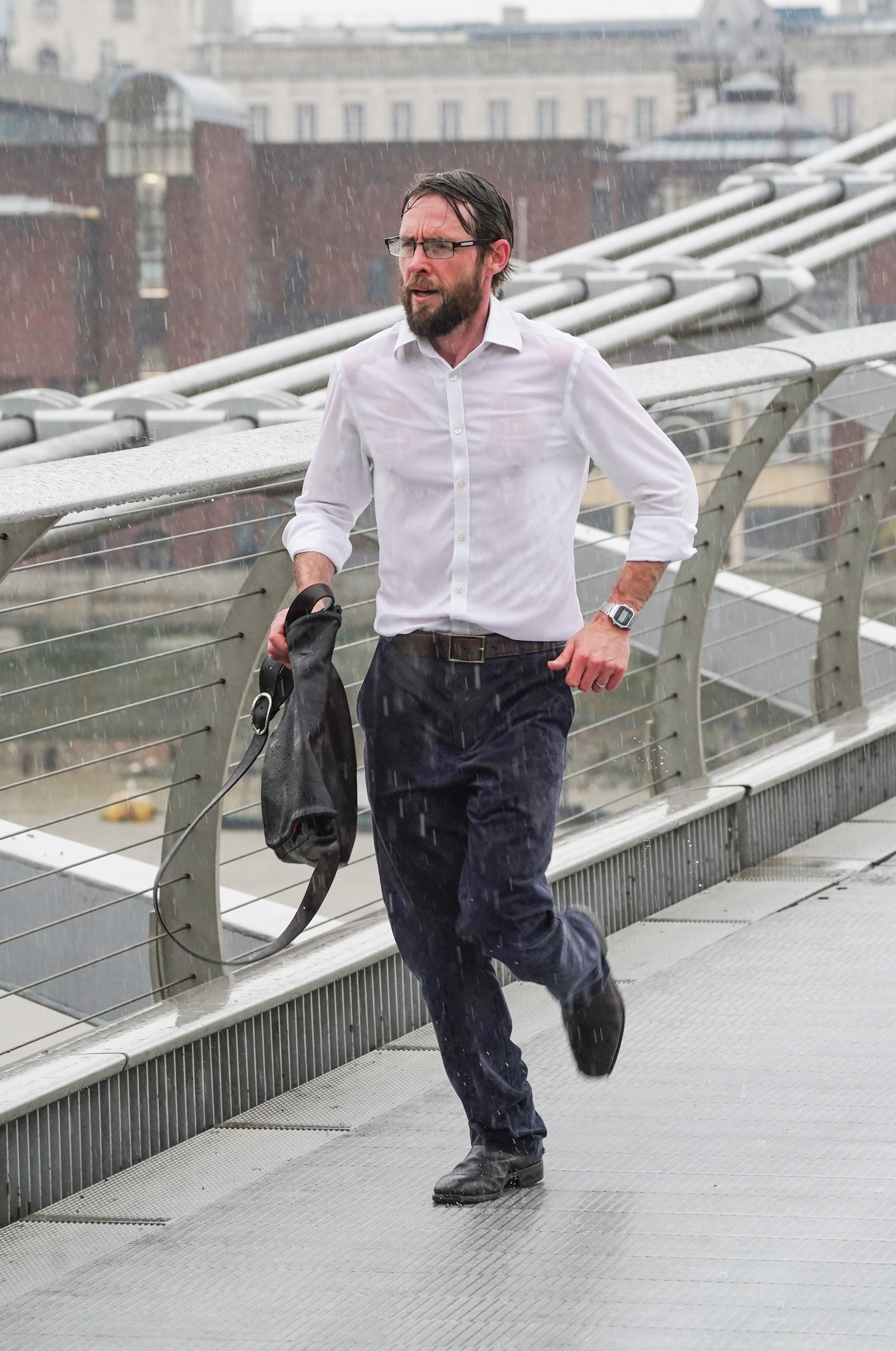 A man runs across the Millennium Bridge in the rain