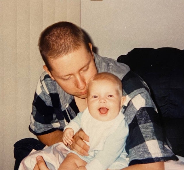 A baby Caitlin sits happily on the lap of her father, Curtis, who died when she was three and a half years old