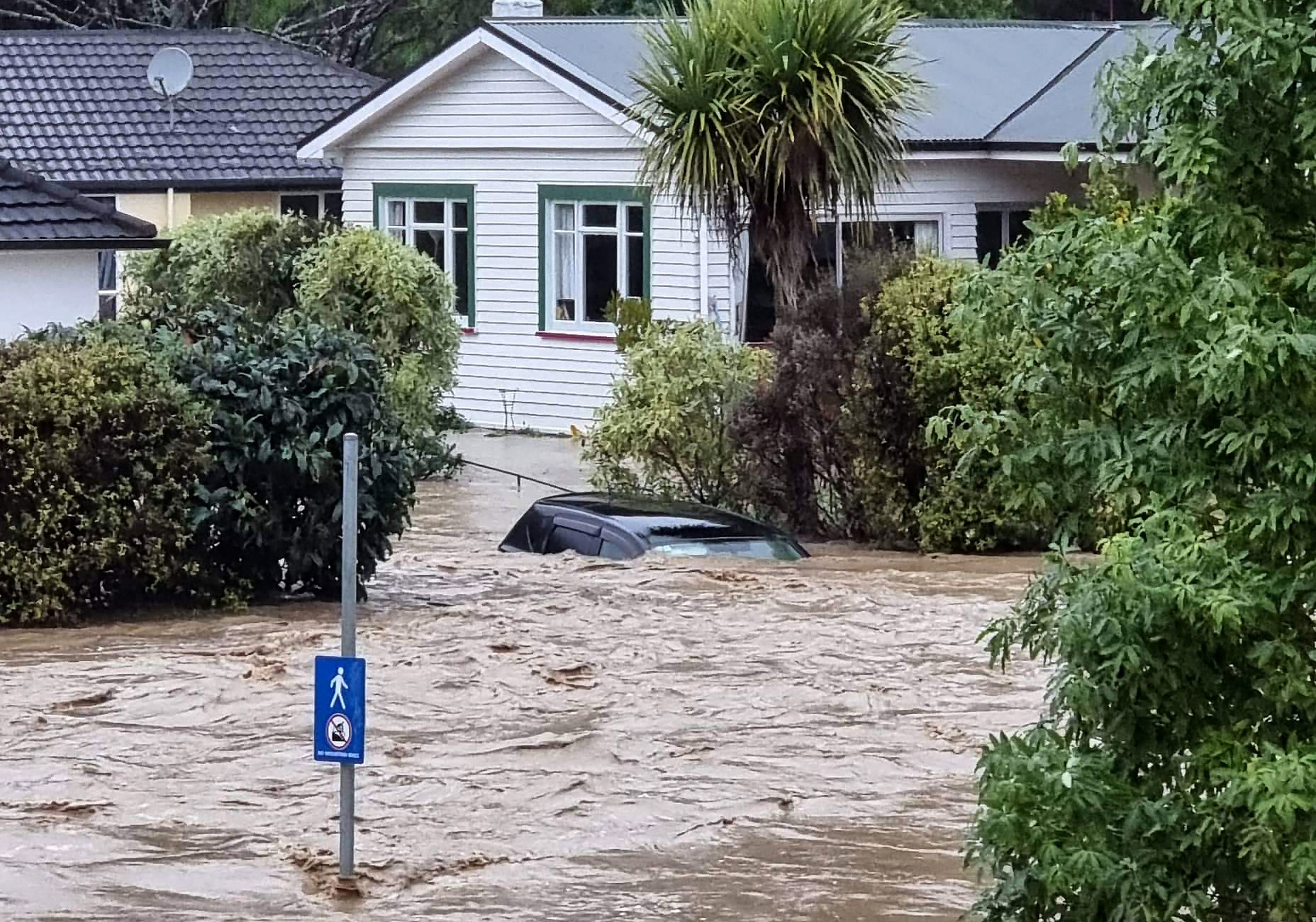 A flood-inundated car and homes from the overflowing Maitai river in central Nelson