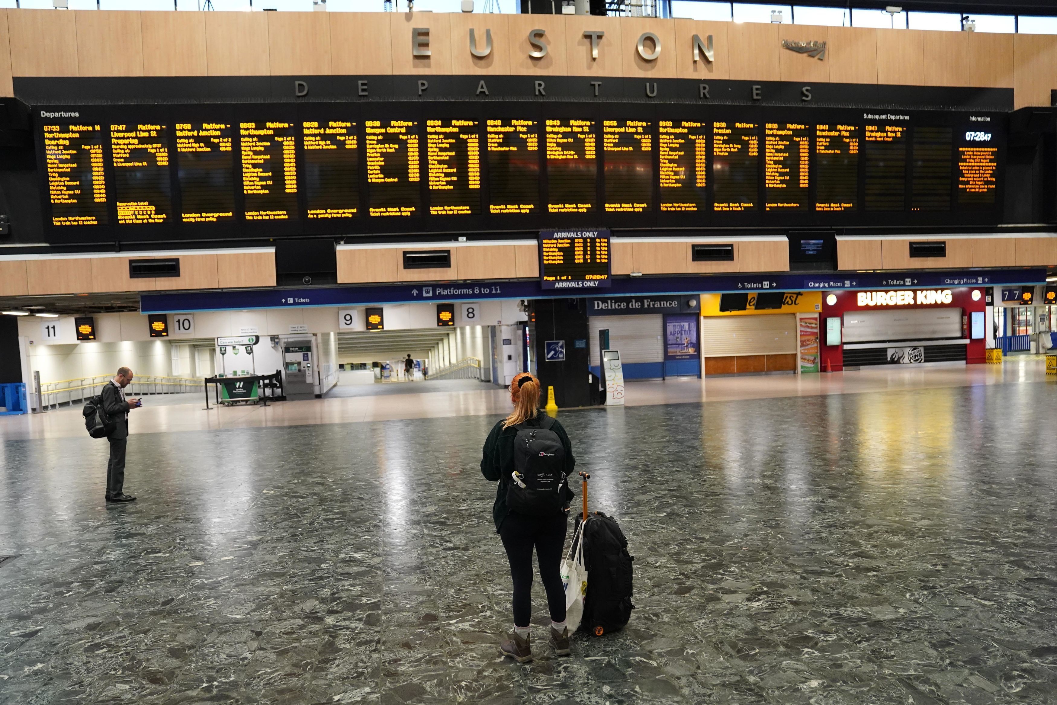 Waiting game: a passenger at London Euston in August