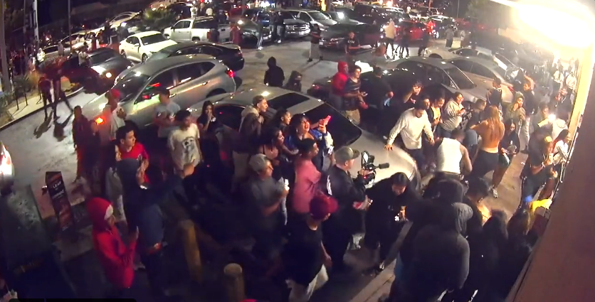 A flash mob of more than a dozen people began forming outside a 7-11 after several cars parked in the middle of a busy intersection to do donuts