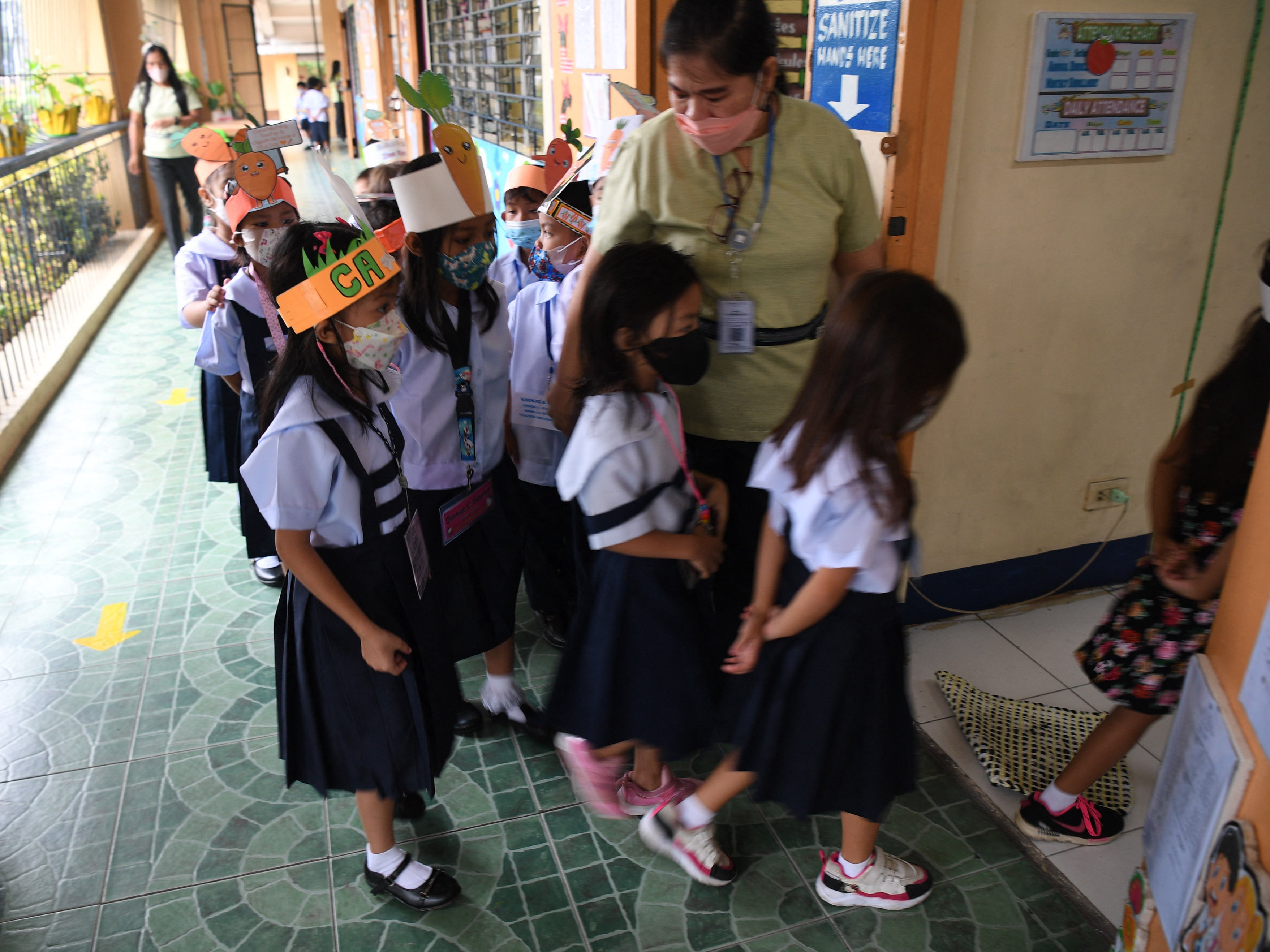 A teacher watches her students walk inside a classroom after a short break at the start of classes at a school in Quezon City, suburban Manila on 22 August 2022