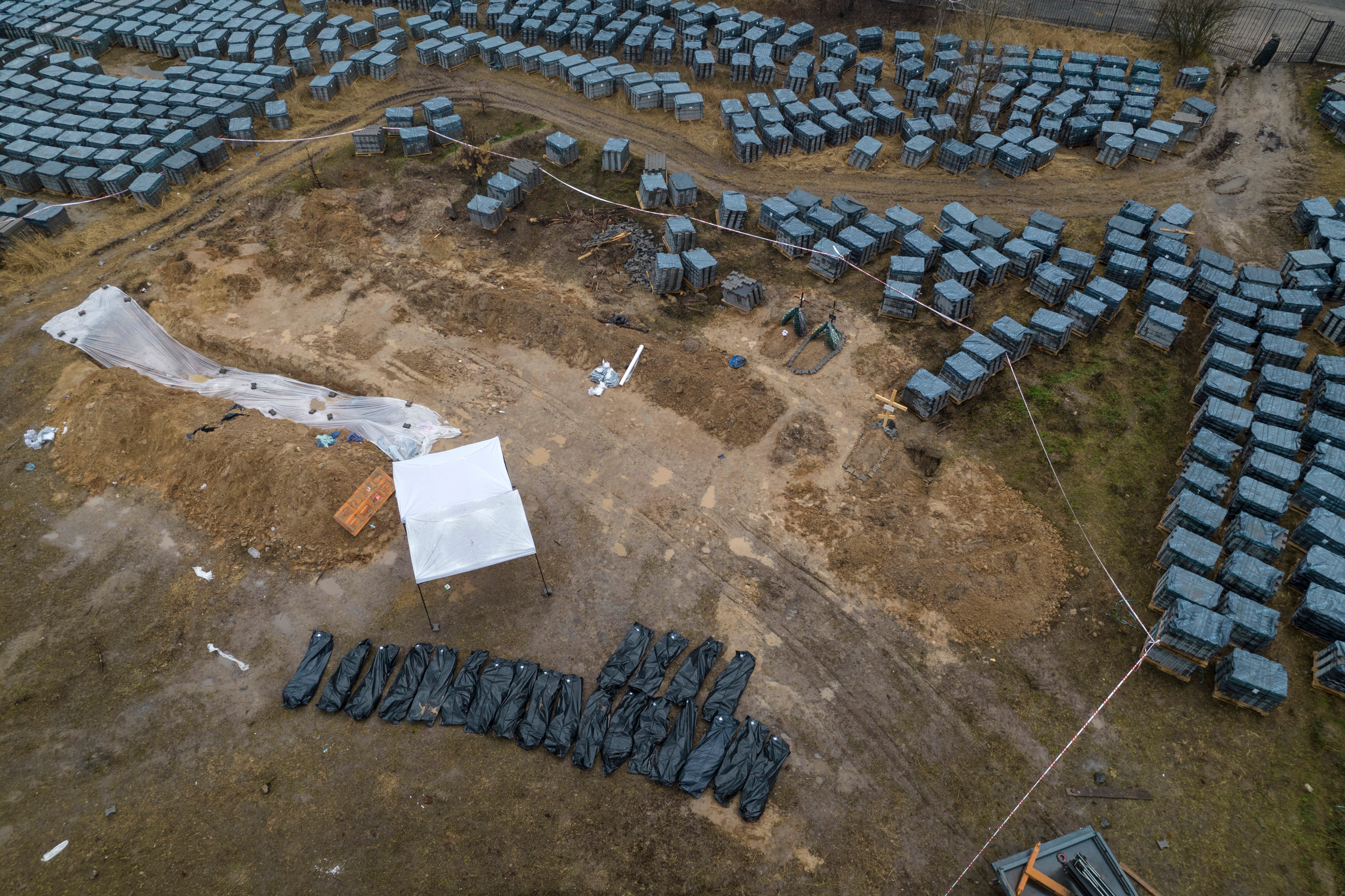 Plastic bags with corpses exhumed from a mass grave are lined up in Bucha, on the outskirts of Kyiv