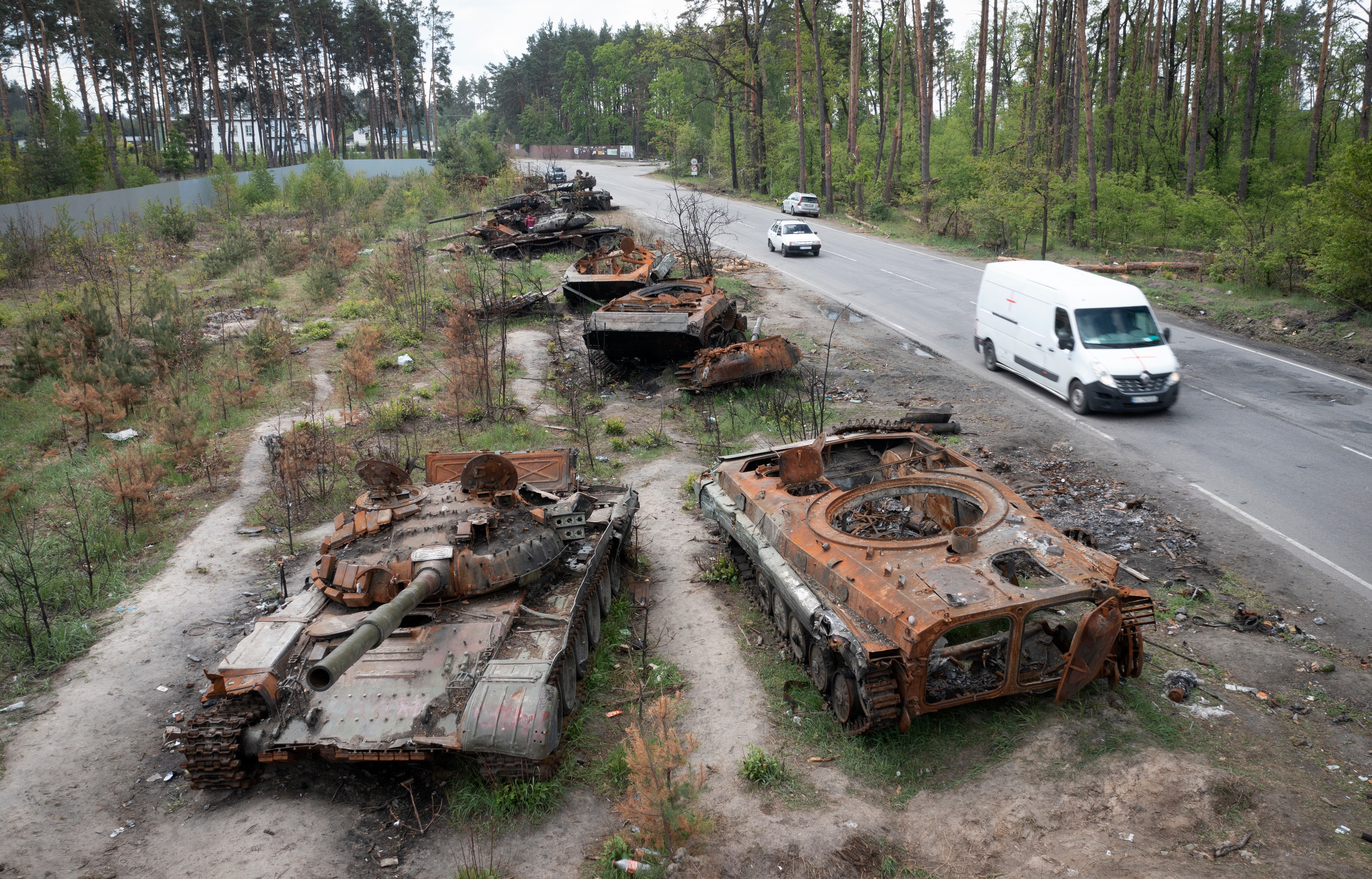 Cars pass by destroyed Russian tanks in the village of Dmytrivka, close to Kyiv