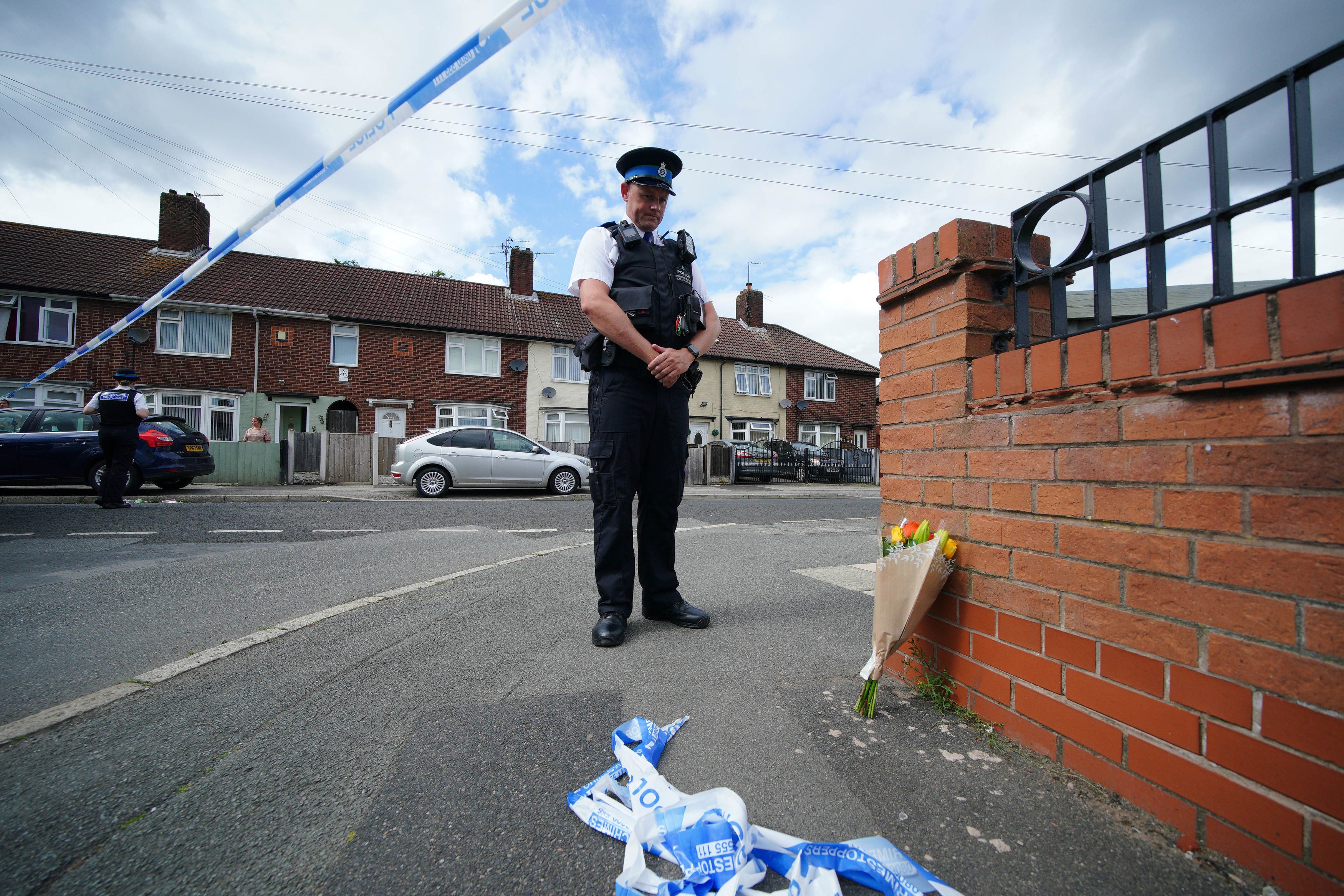 A police officer lays flowers on Tuesday near the scene in Knotty Ash, Liverpool, where nine-year-old Olivia Pratt-Korbel was fatally shot