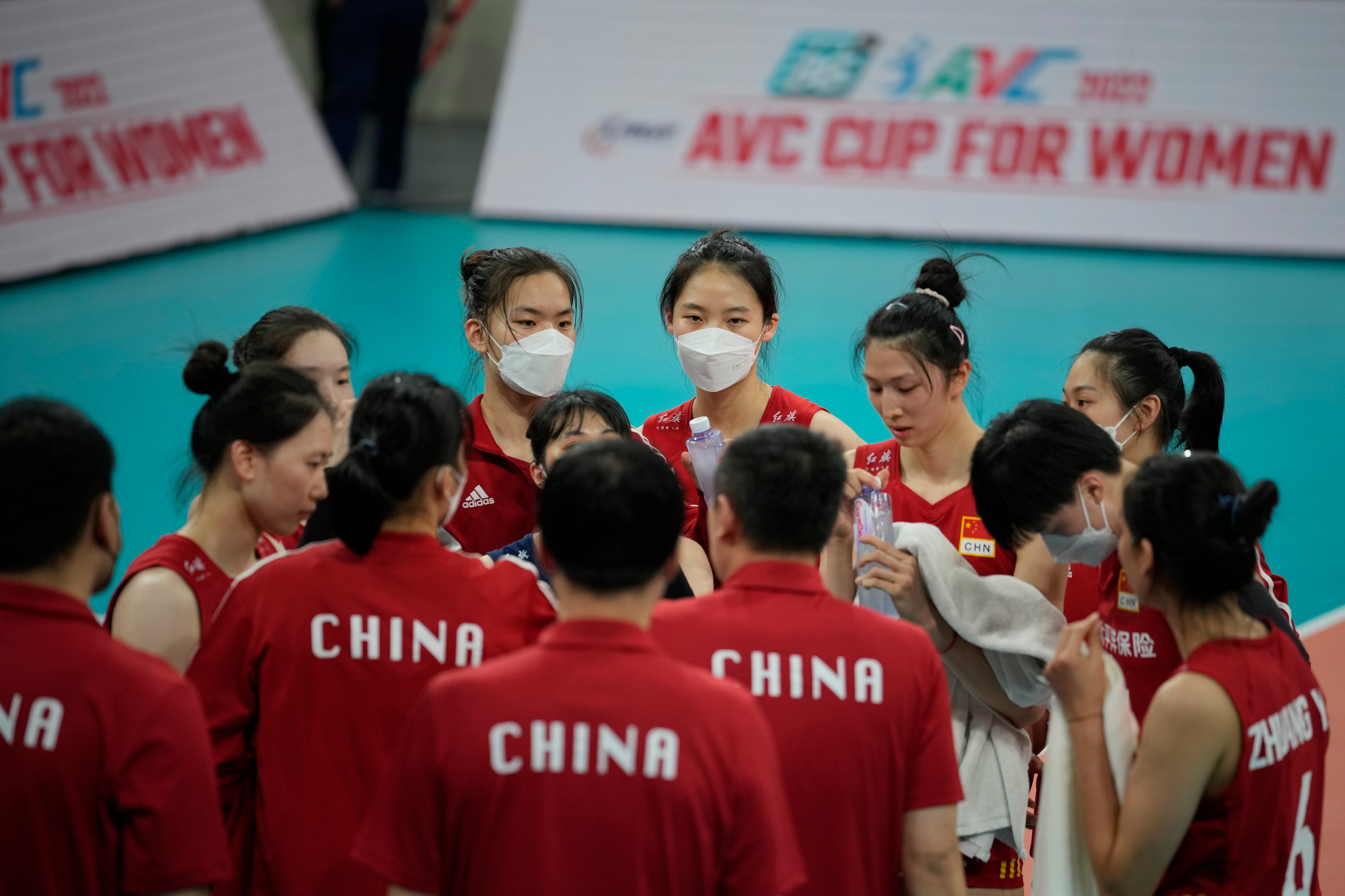 Chinese players, some wearing face masks, gather during their preliminary match against Iran