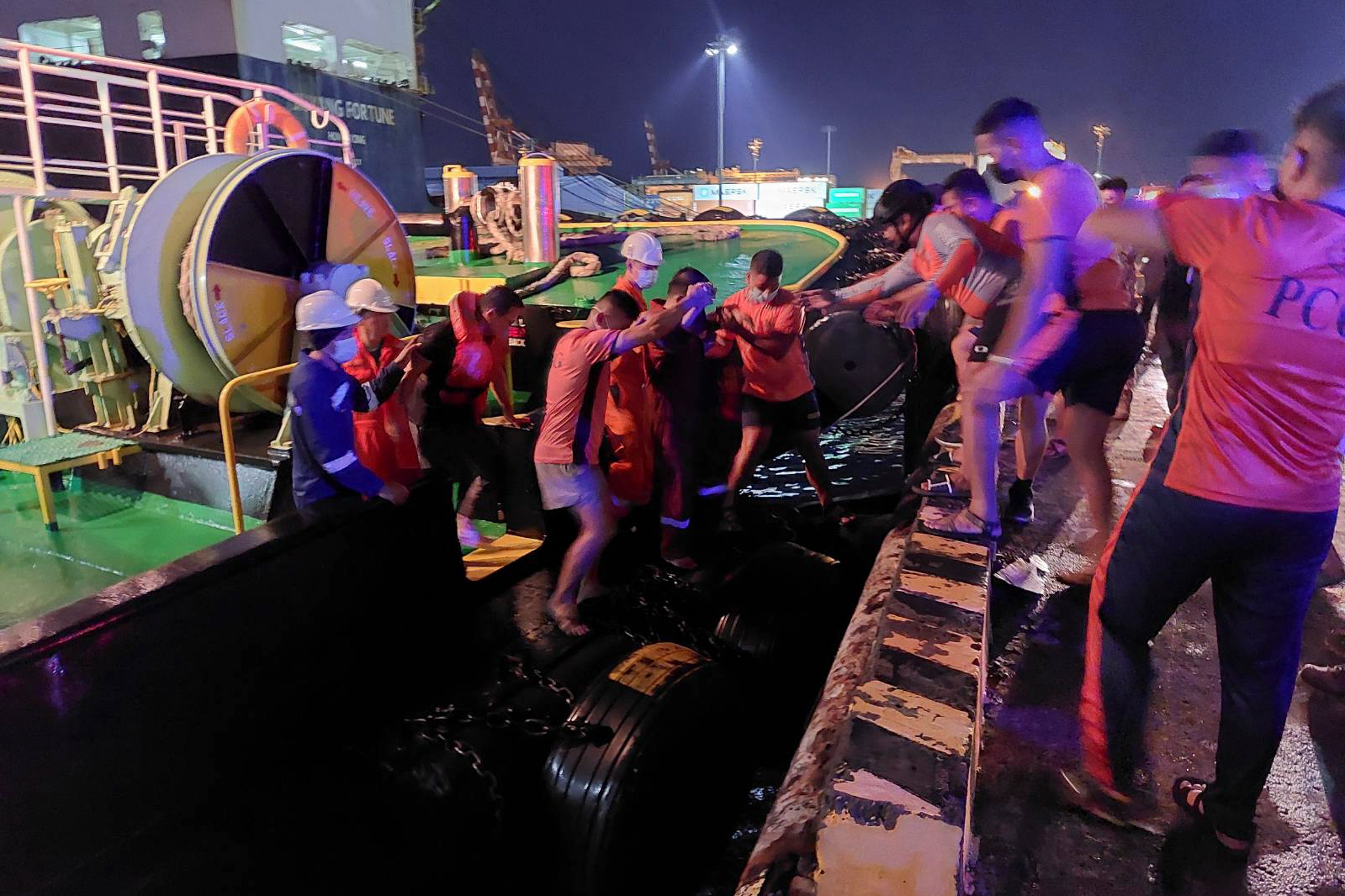 Rescuers assist people as the M/V Asia Philippines, an inter-island cargo and passenger vessel, they were riding caught fire