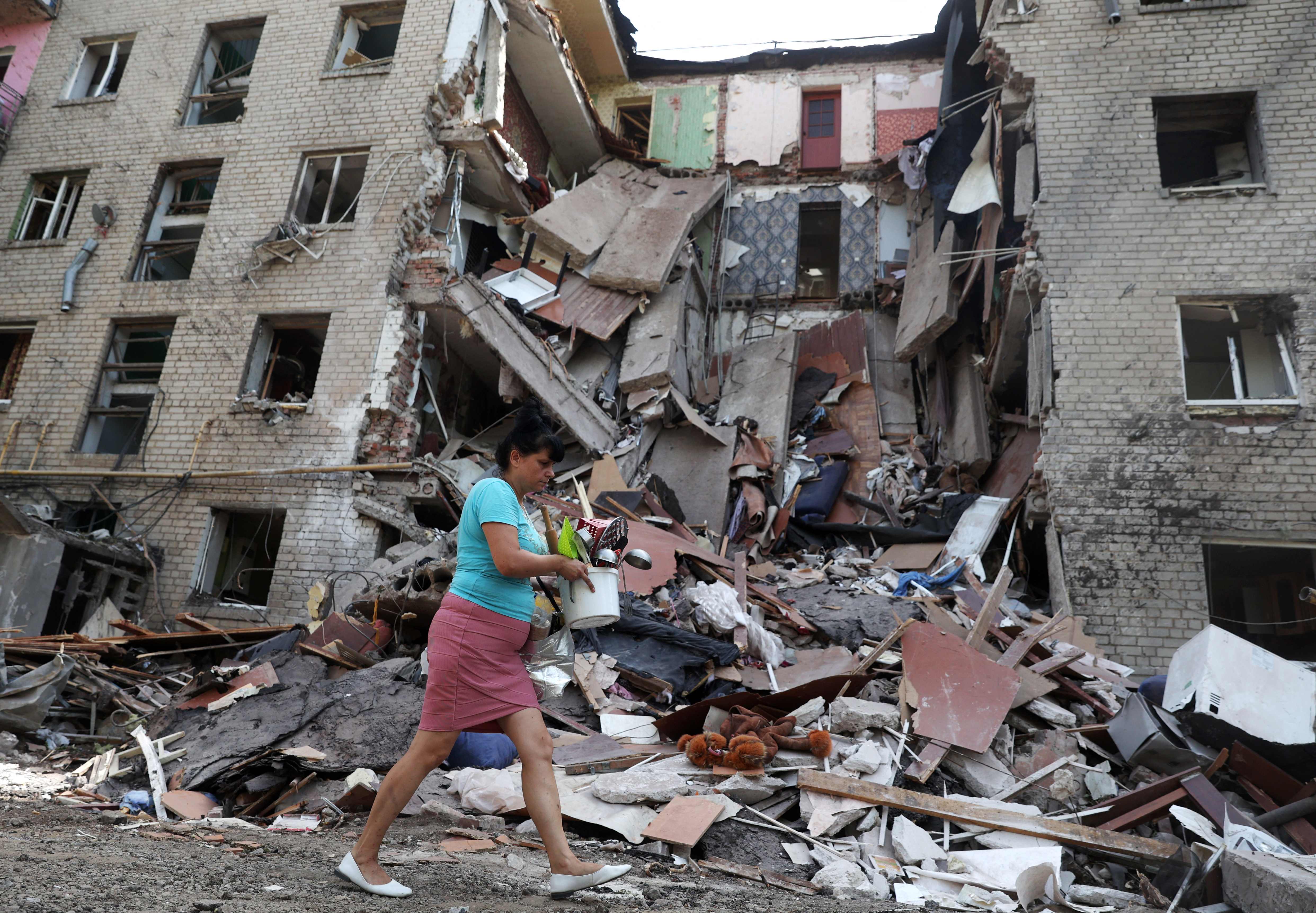 A woman takes her belongings from a heavily damaged residential building after a strike in the town of Bakhmut, Donetsk, on Sunday