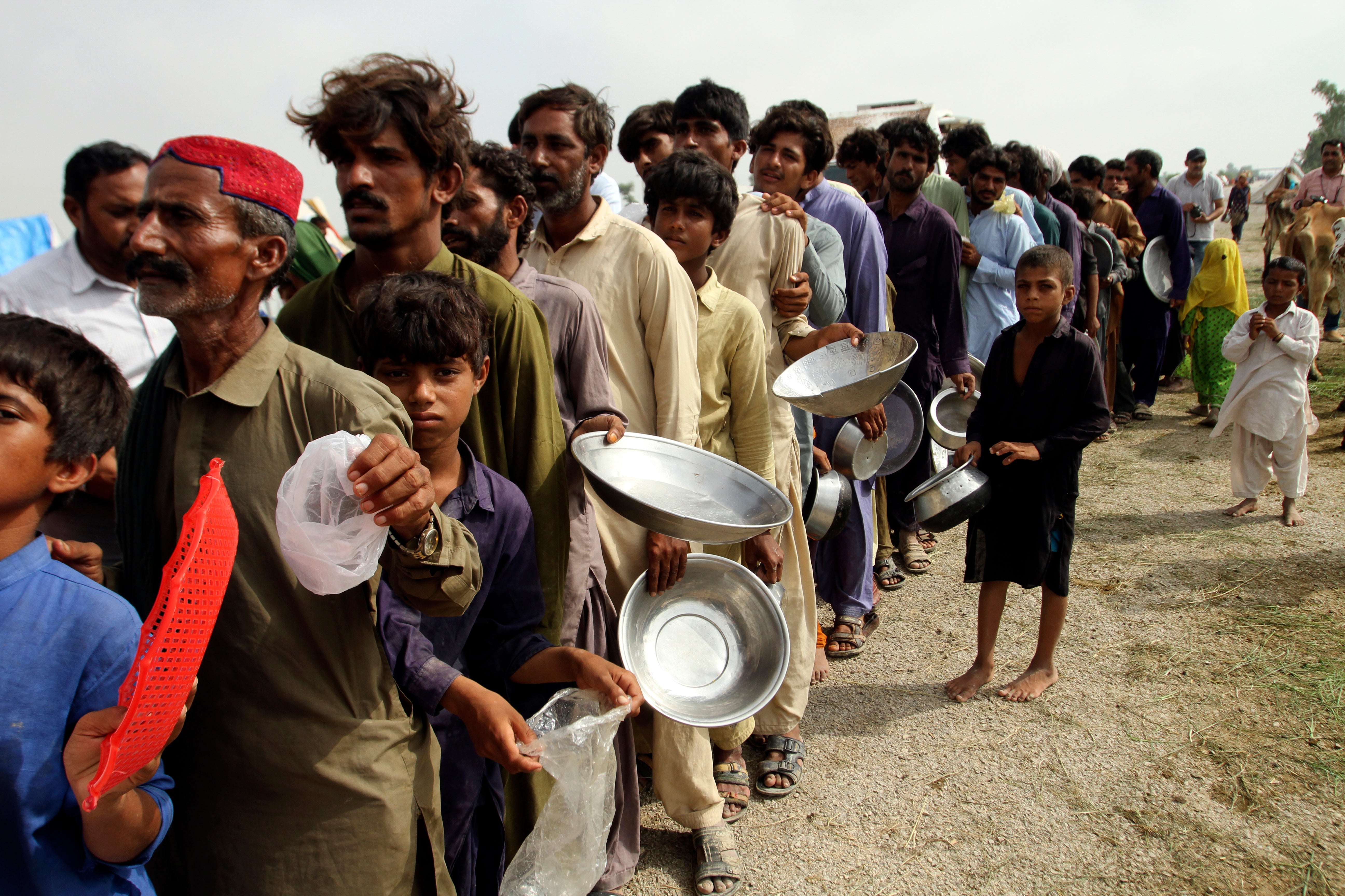 Flood affected people stand in a long line with utensils to get food distributed by Pakistani Army troops in a flood-hit area in Rajanpur, district of Punjab, Pakistan