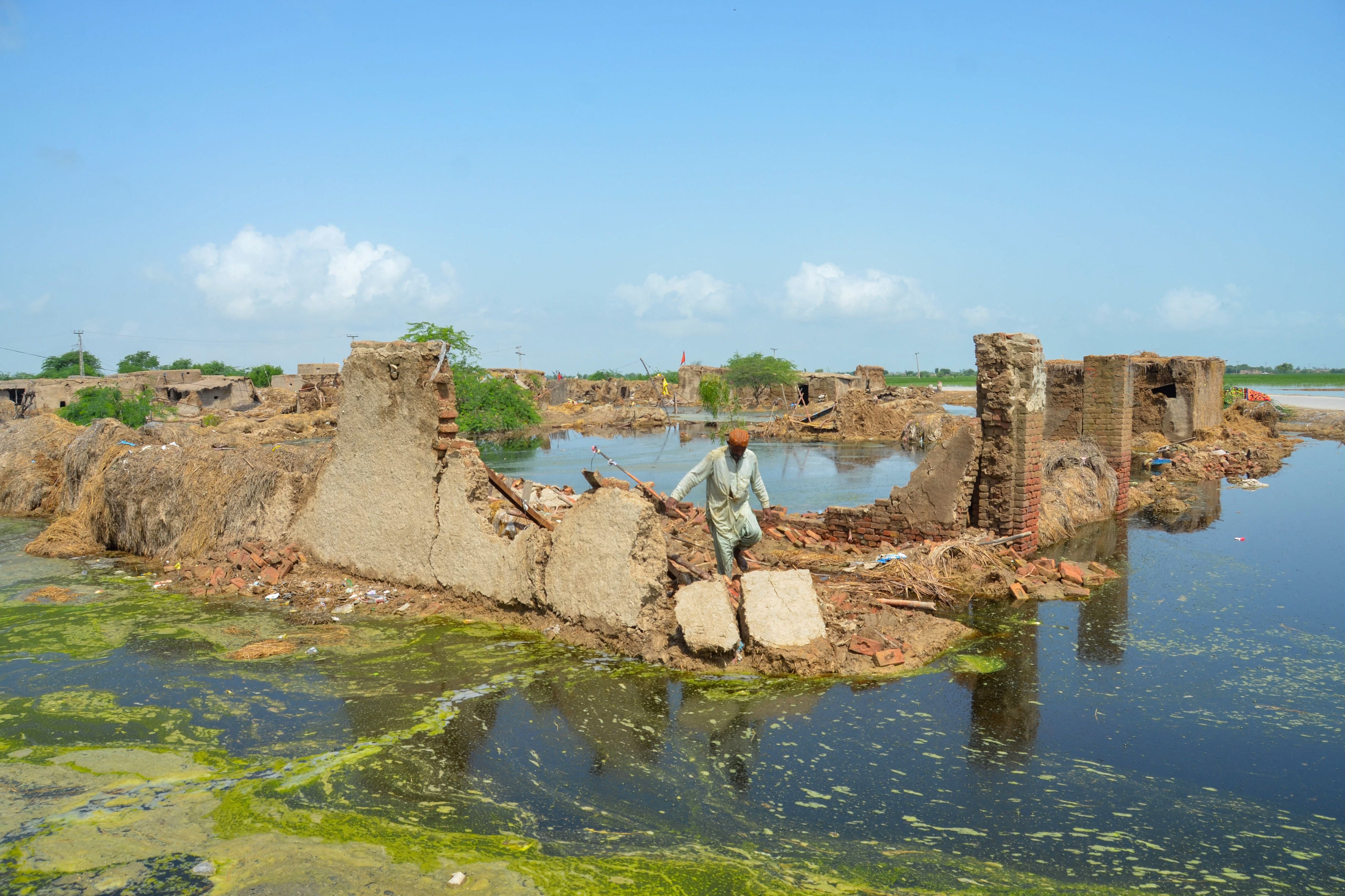 A flood affected man walks over his collapsed mud house after heavy monsoon rains in Jaffarabad district, Balochistan