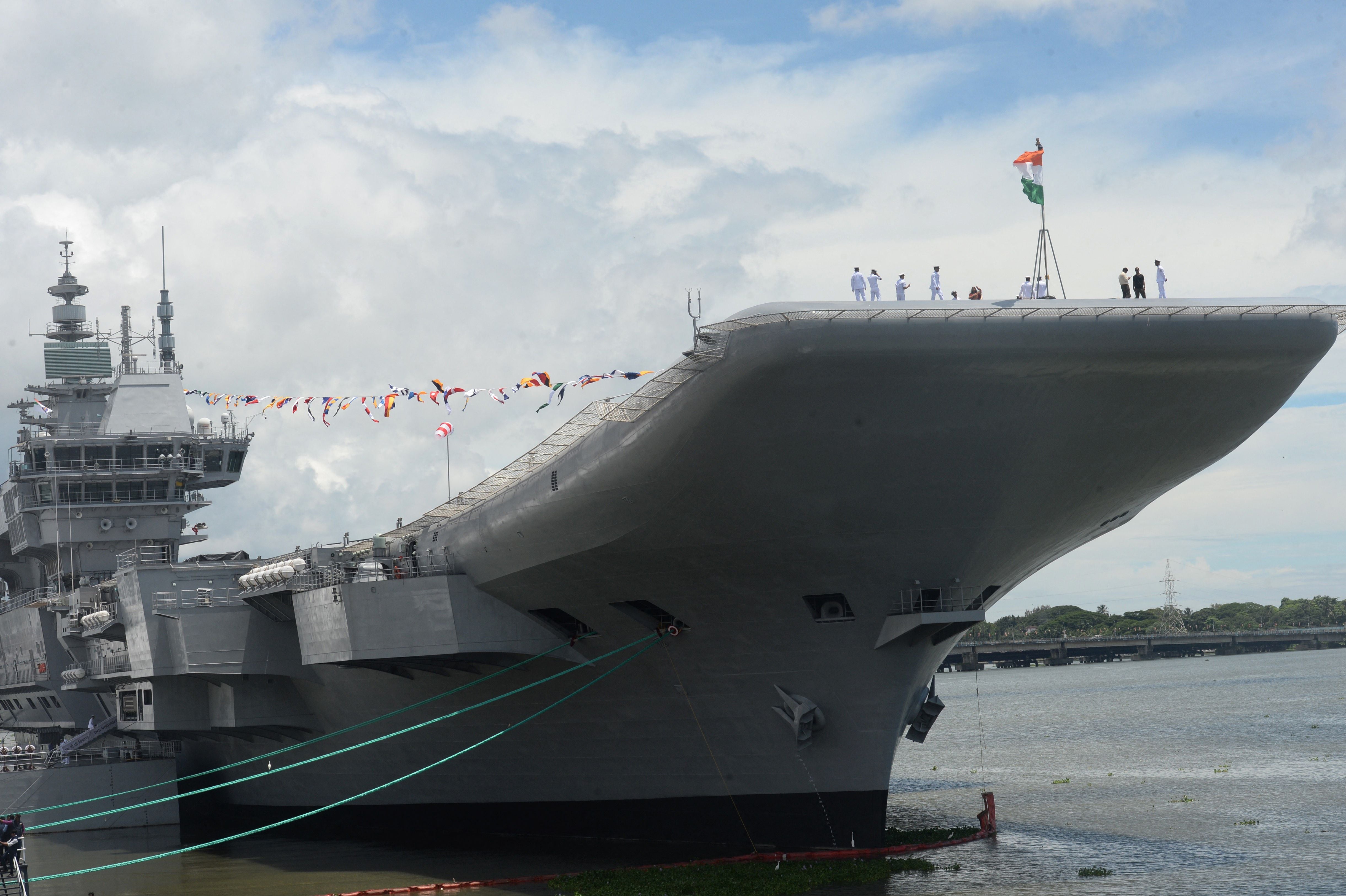 Indian Navy officers gather on the deck of INS Vikrant during its commissioning at Cochin Shipyard on 2 September