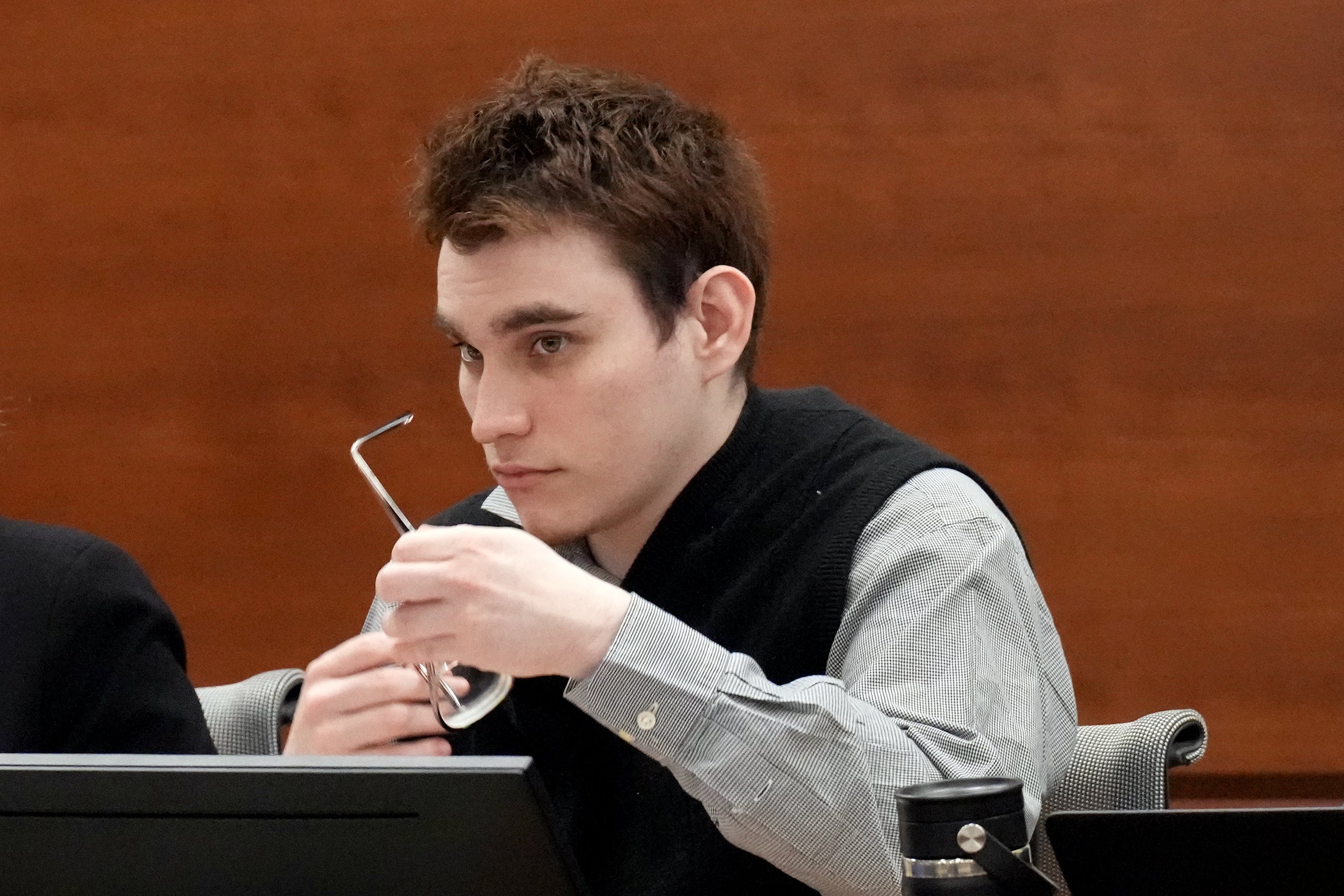 Nikolas Cruz cleans his glasses as he listens in court on Friday 2 September