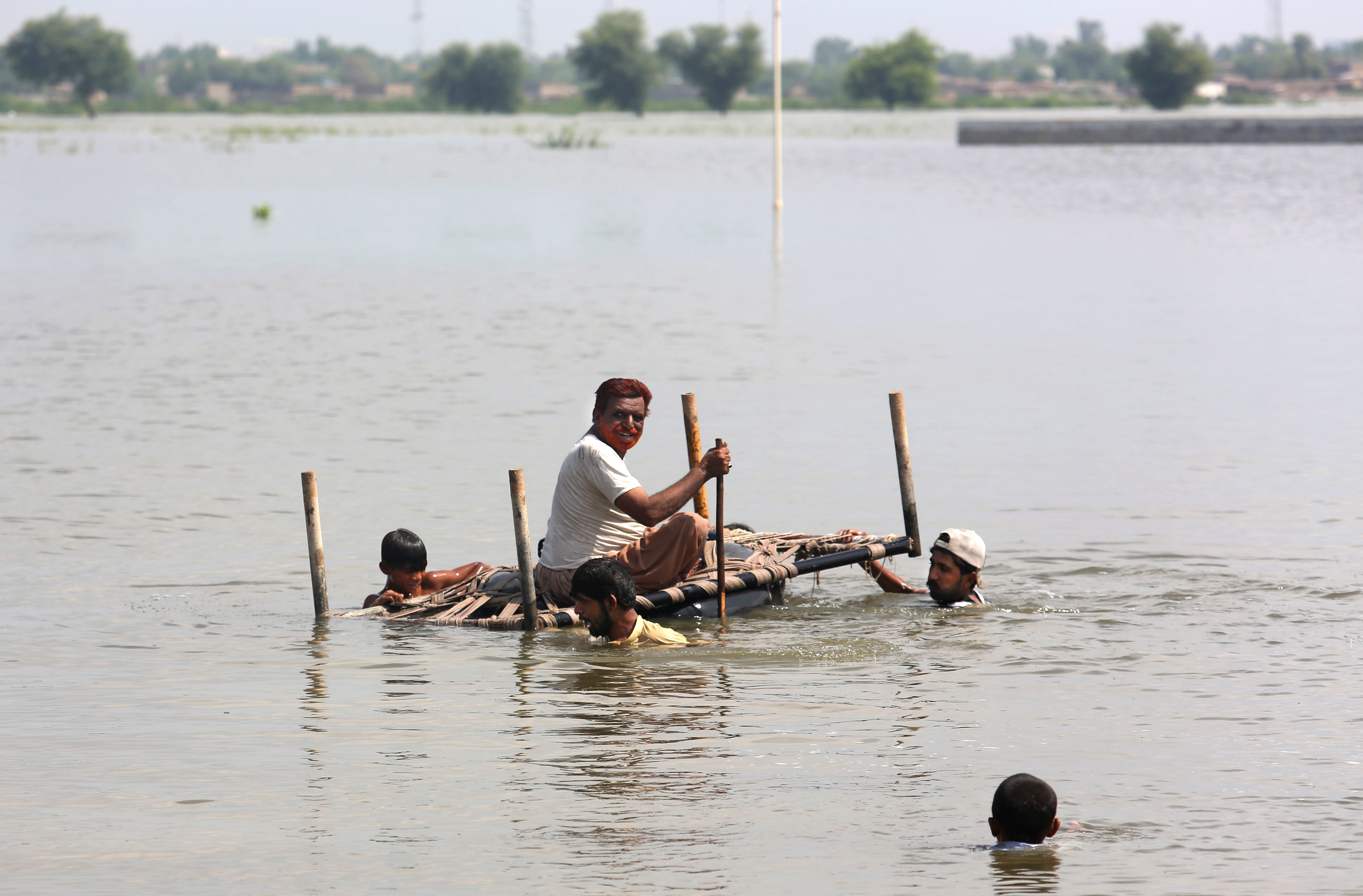 People try to salvage belongings from their nearby flooded home caused by heavy rain in Pakistan (Fareed Khan/AP)