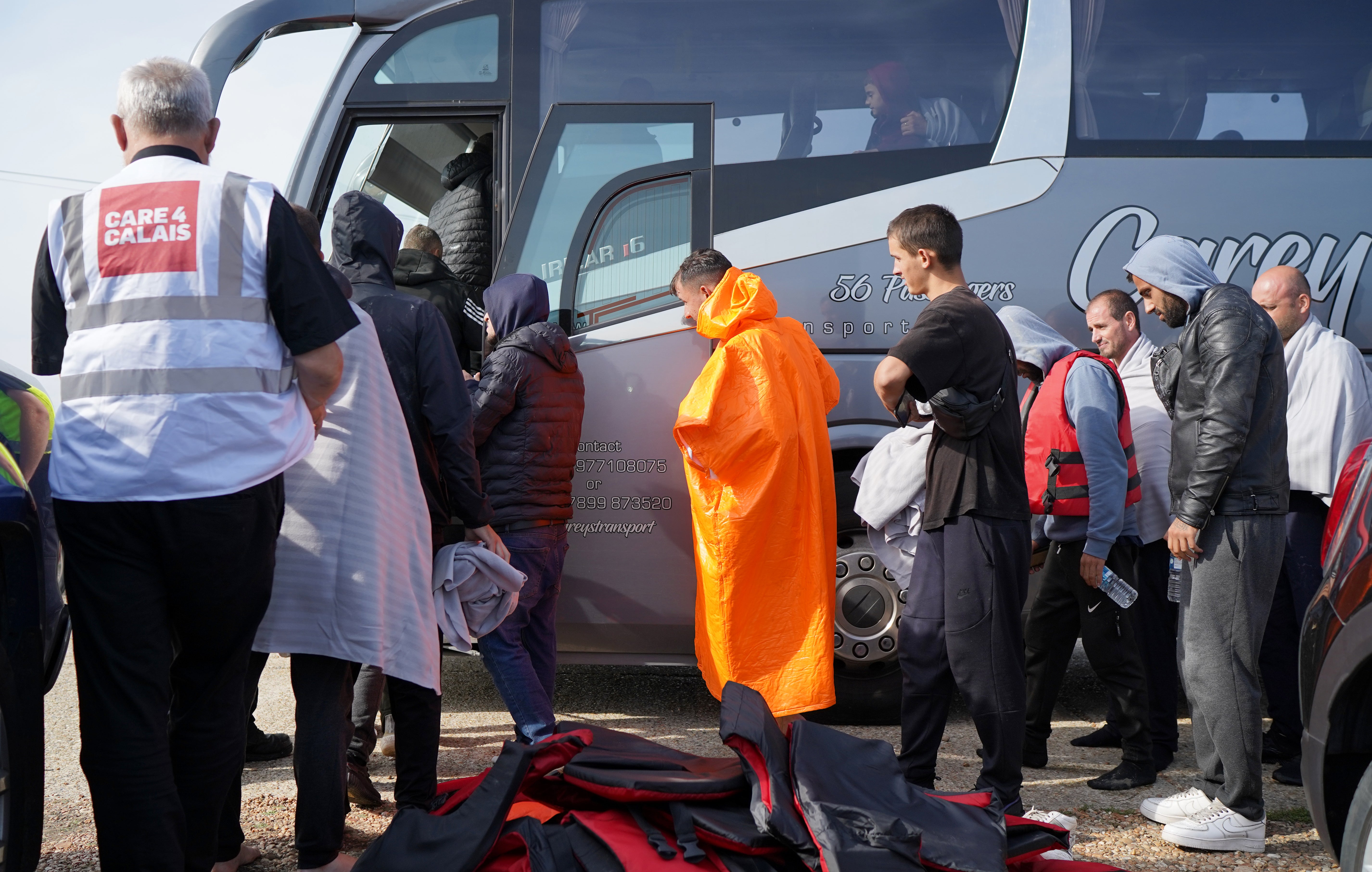 A group of people thought to be migrants are escorted on to a bus in Dungeness, Kent, after being intercepted by the Dungeness Lifeboat (Gareth Fuller/PA)